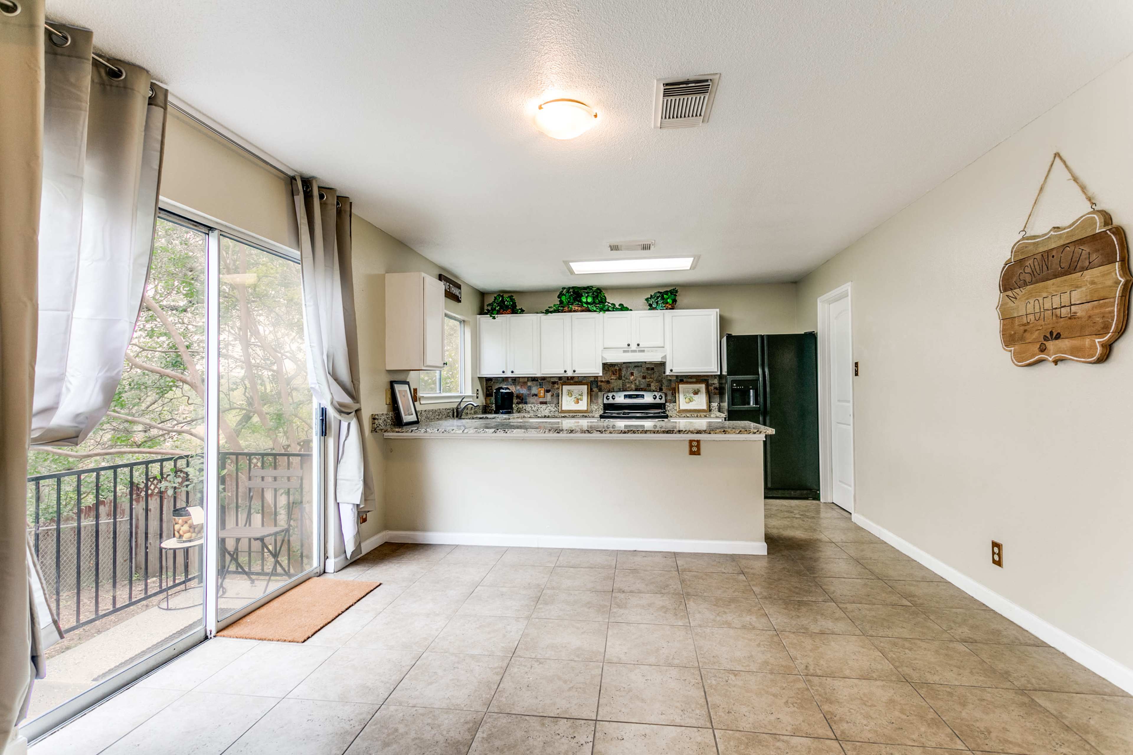 A spacious kitchen area features granite countertops, white cabinets, and large windows overlooking a balcony.