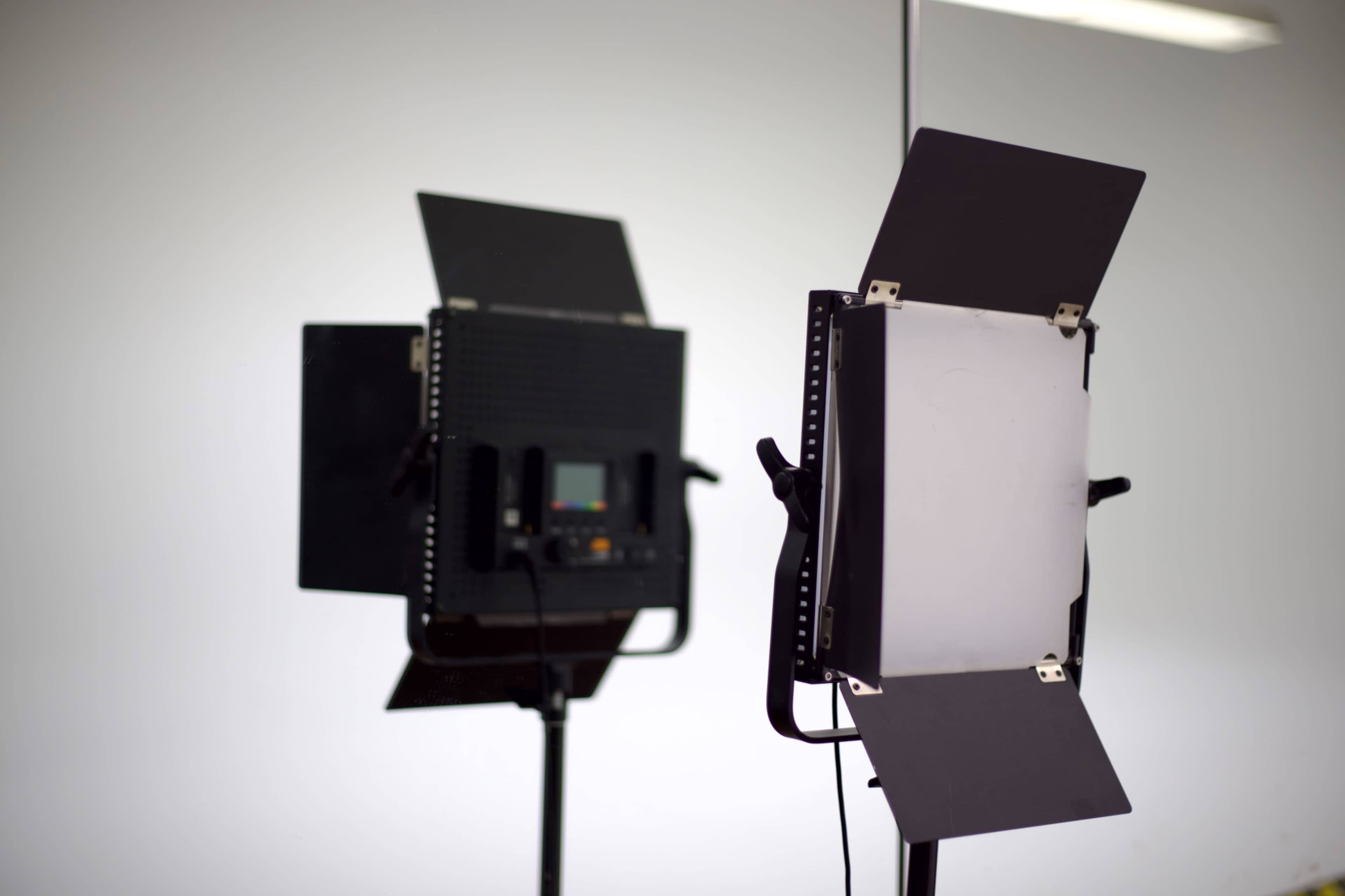 A studio lighting setup is shown, featuring a light panel mounted on a stand with a reflection in the background.