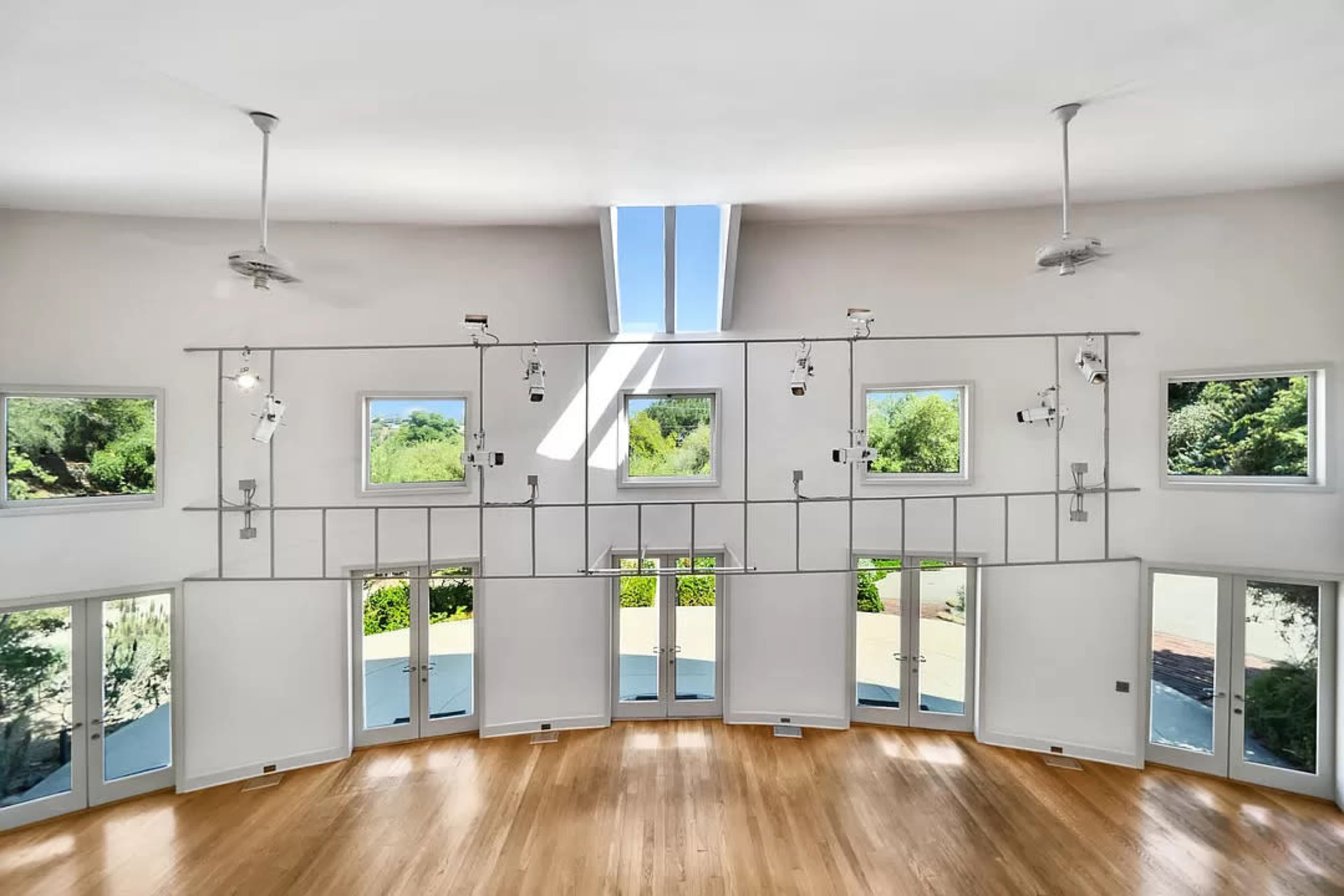 The interior features a circular room with multiple windows and doors, allowing natural light to illuminate the wooden floor.