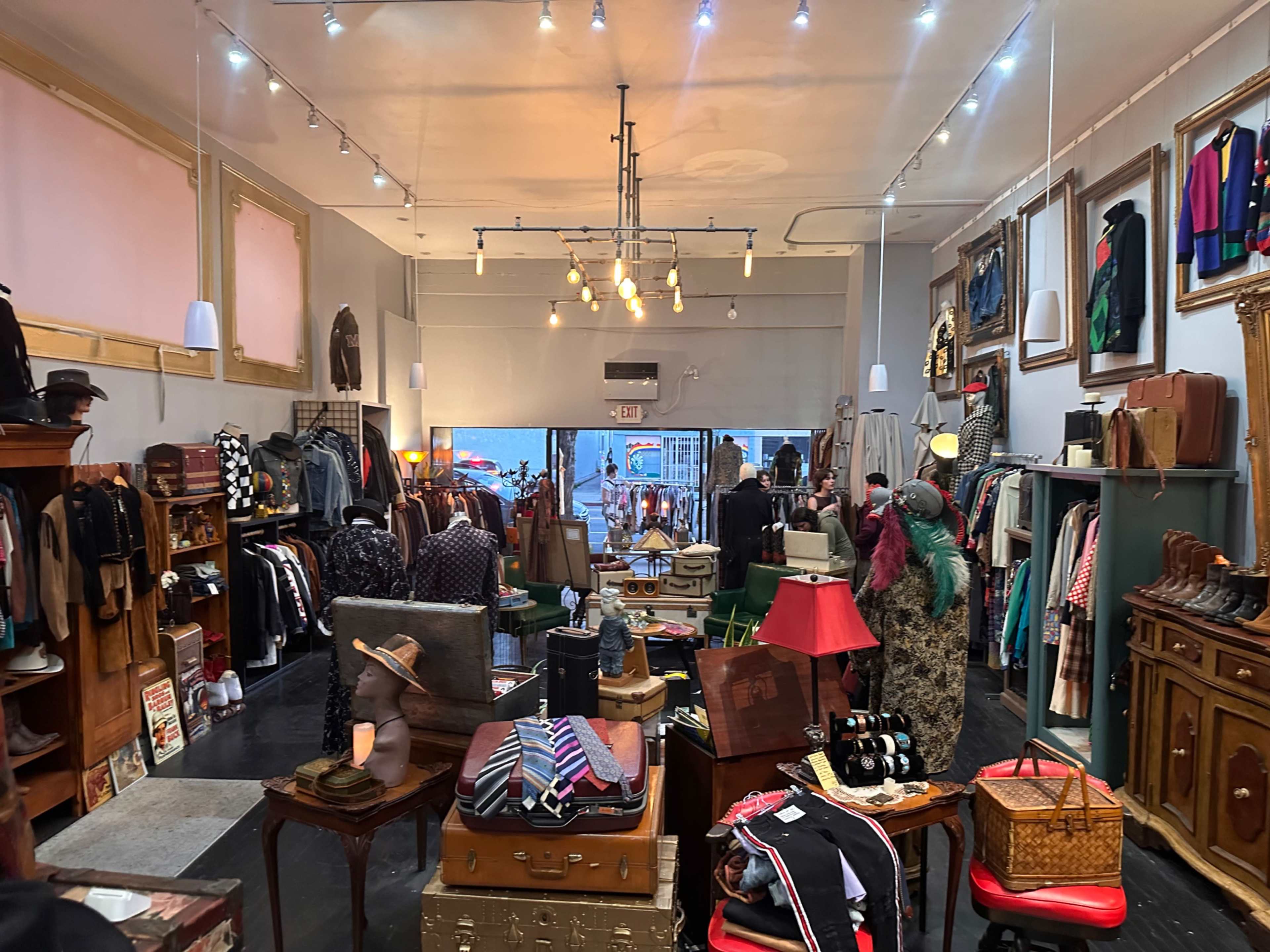 A well-organized vintage clothing store showcases a variety of apparel, accessories, and decor arranged on racks and displays.