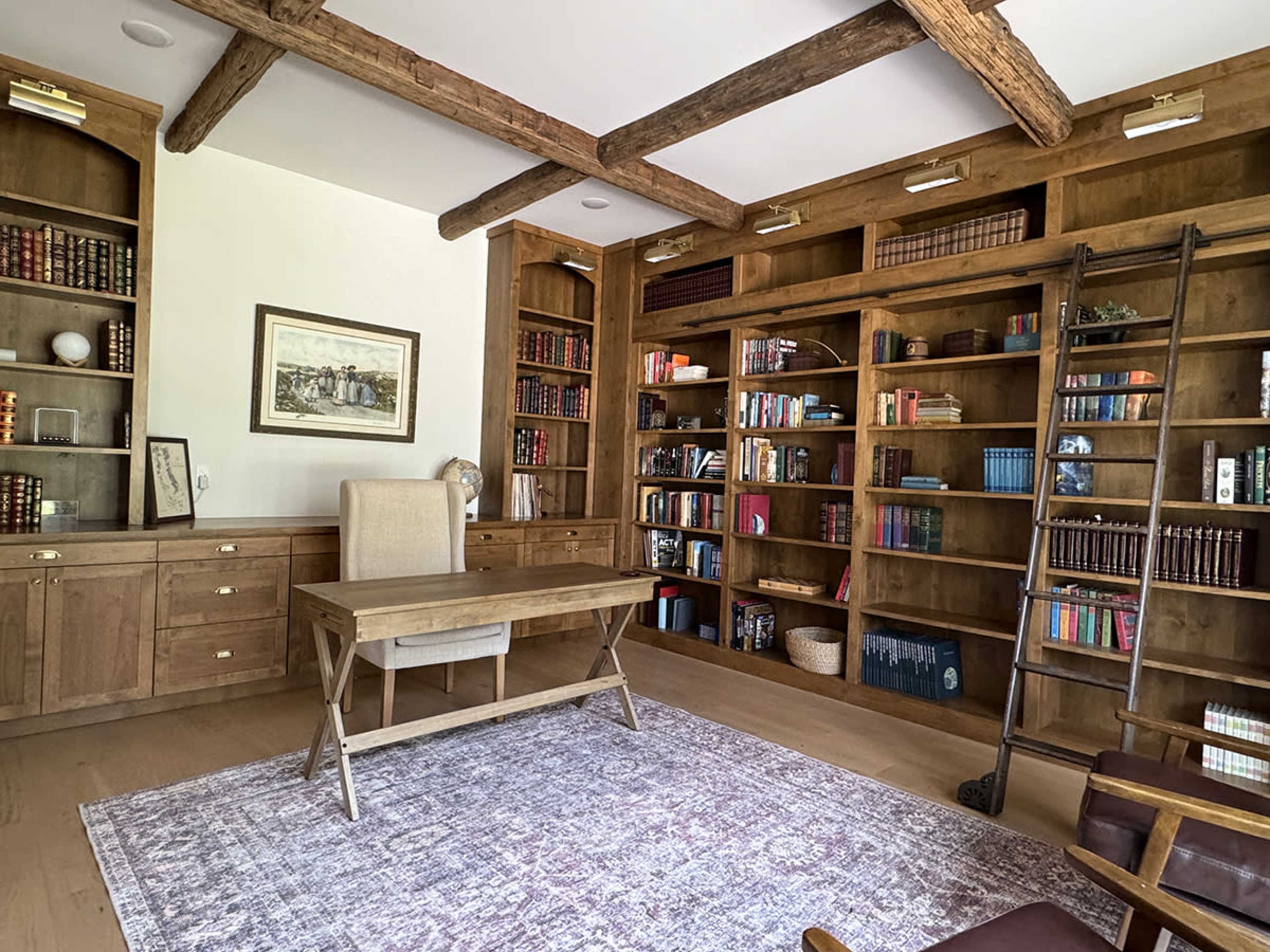 A wooden office features a large desk, bookshelves filled with books, and a decorative ladder against the wall.