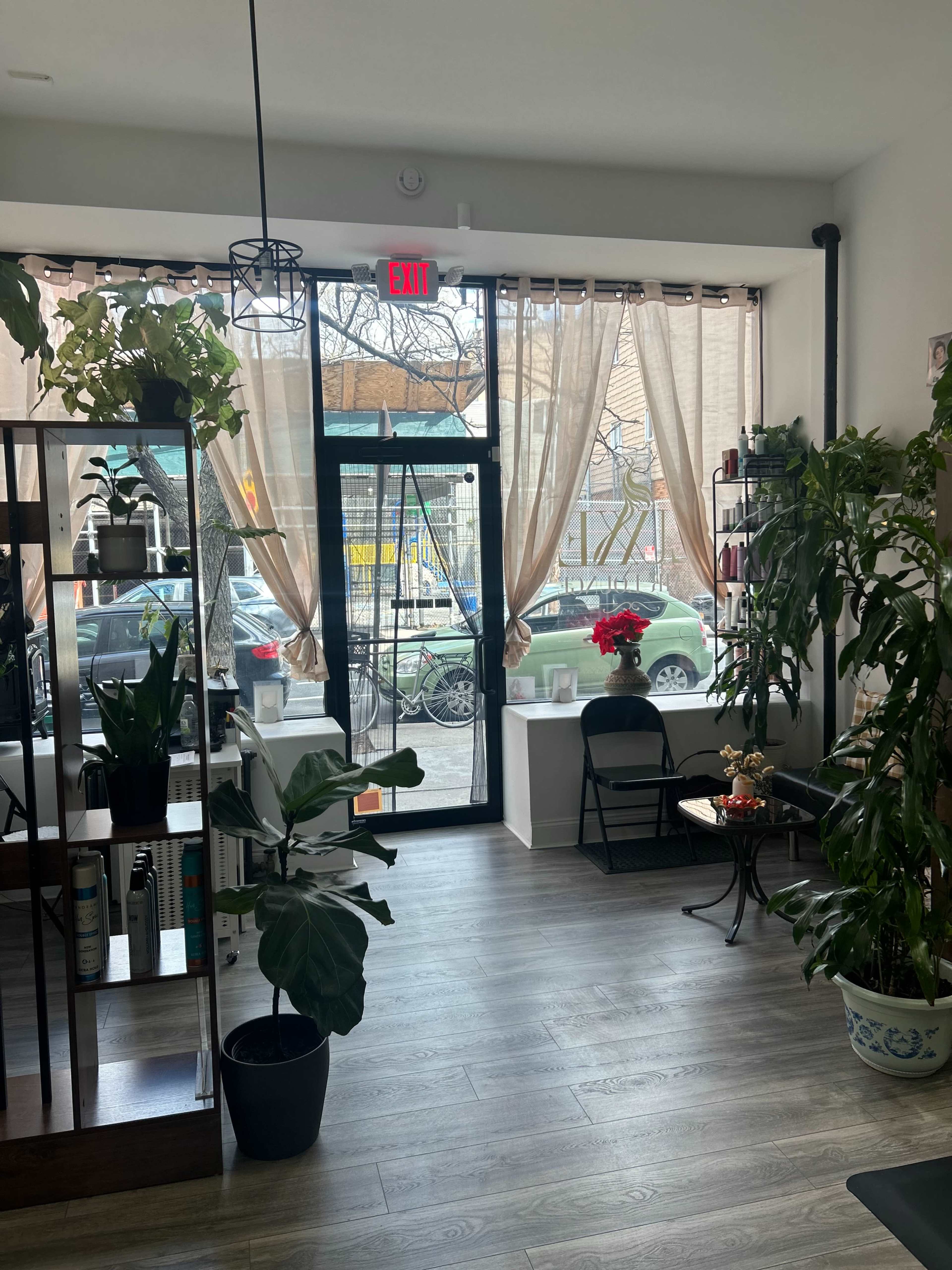 The image displays a bright, inviting interior of a storefront with large windows, plants, and a few chairs.