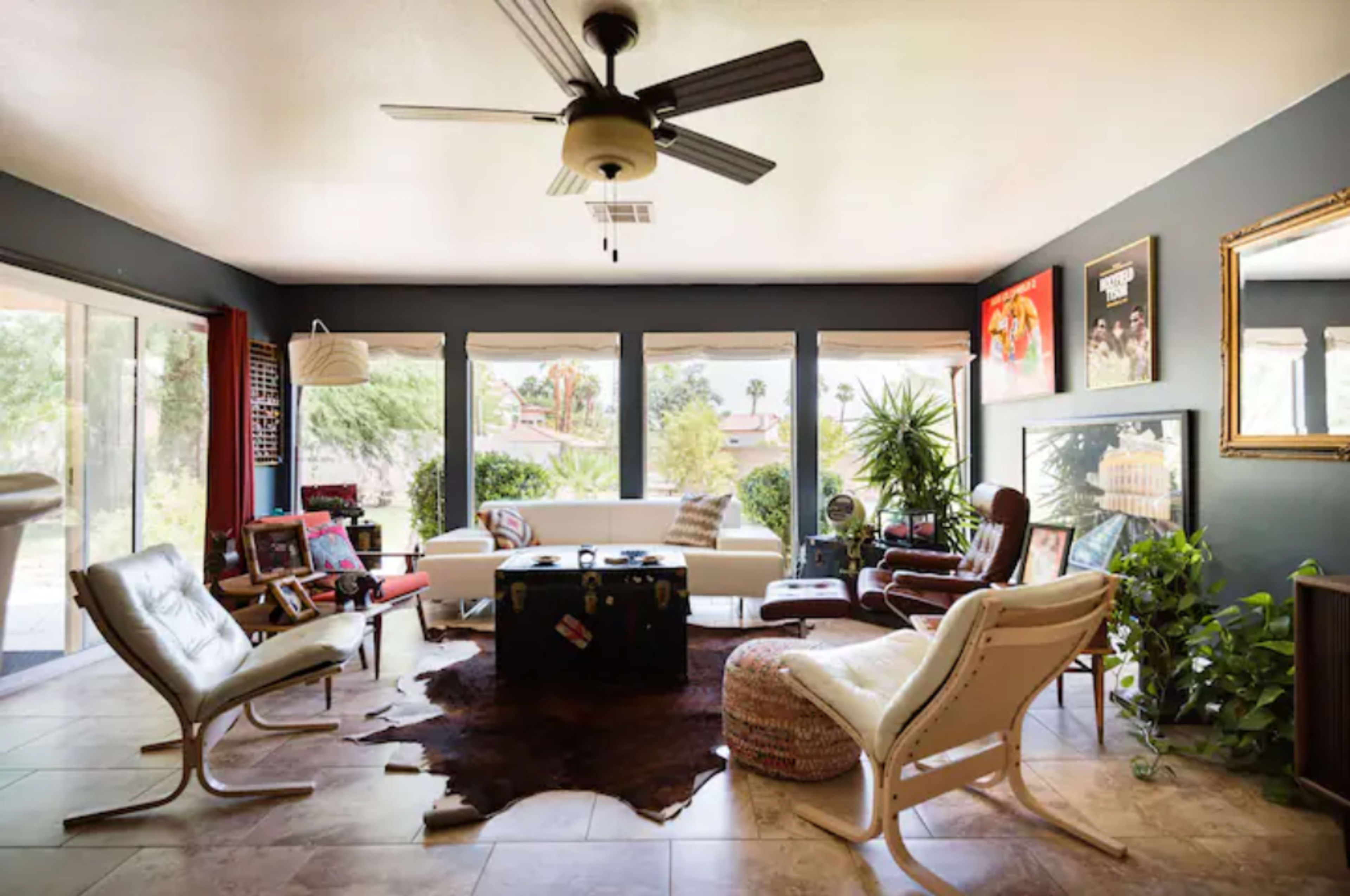 A stylish living room with large windows, a variety of seating options, and decorative plants.