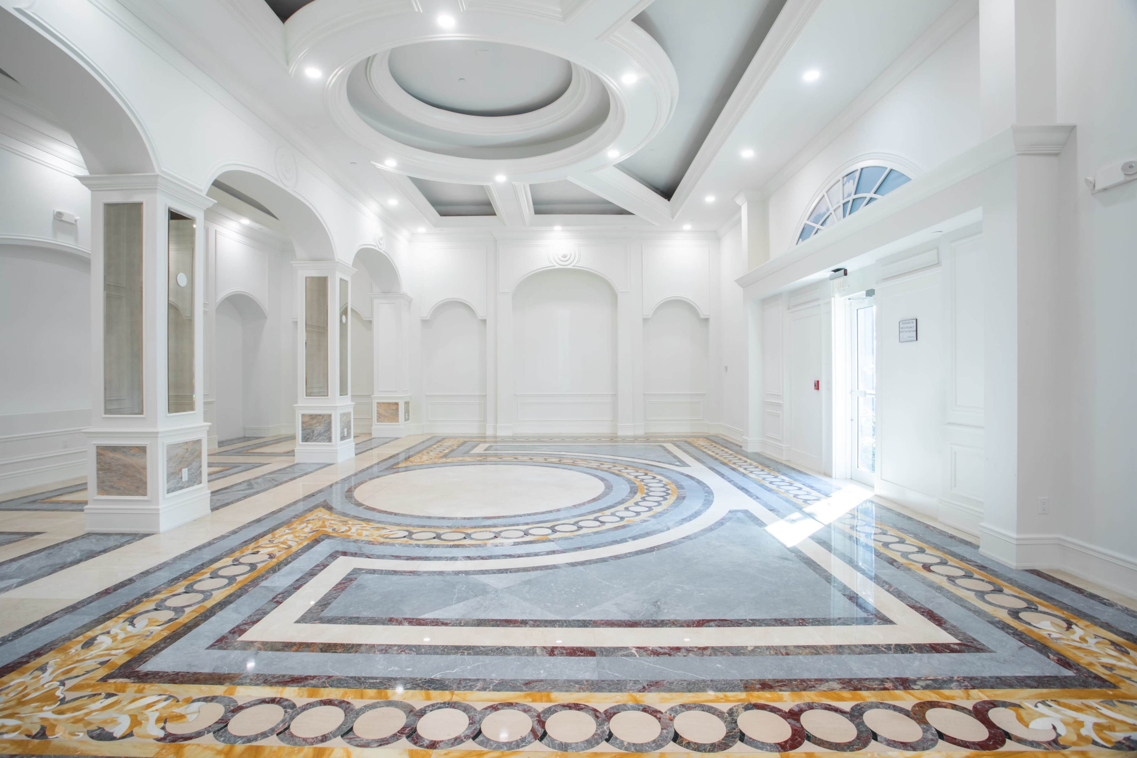 A bright and spacious lobby with intricate marble flooring and elegant architectural details.