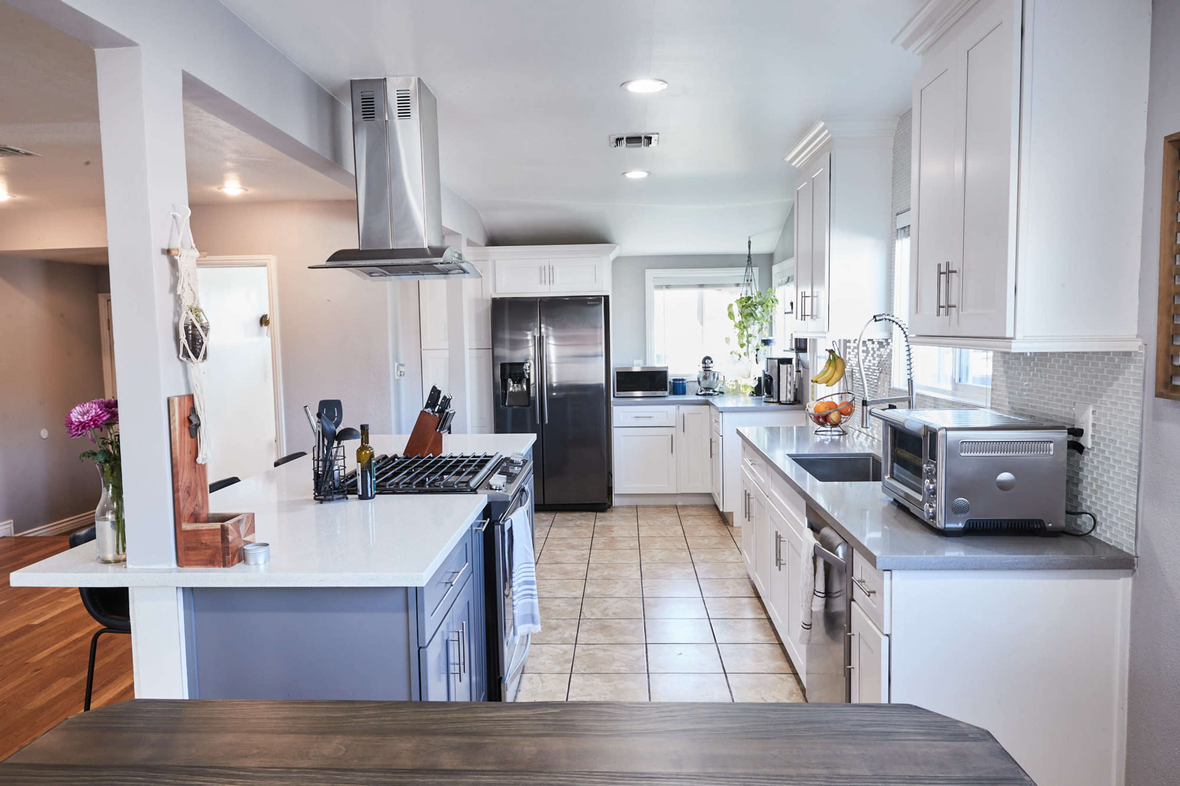 A modern kitchen features stainless steel appliances, white cabinets, and a spacious layout with a centralized island.