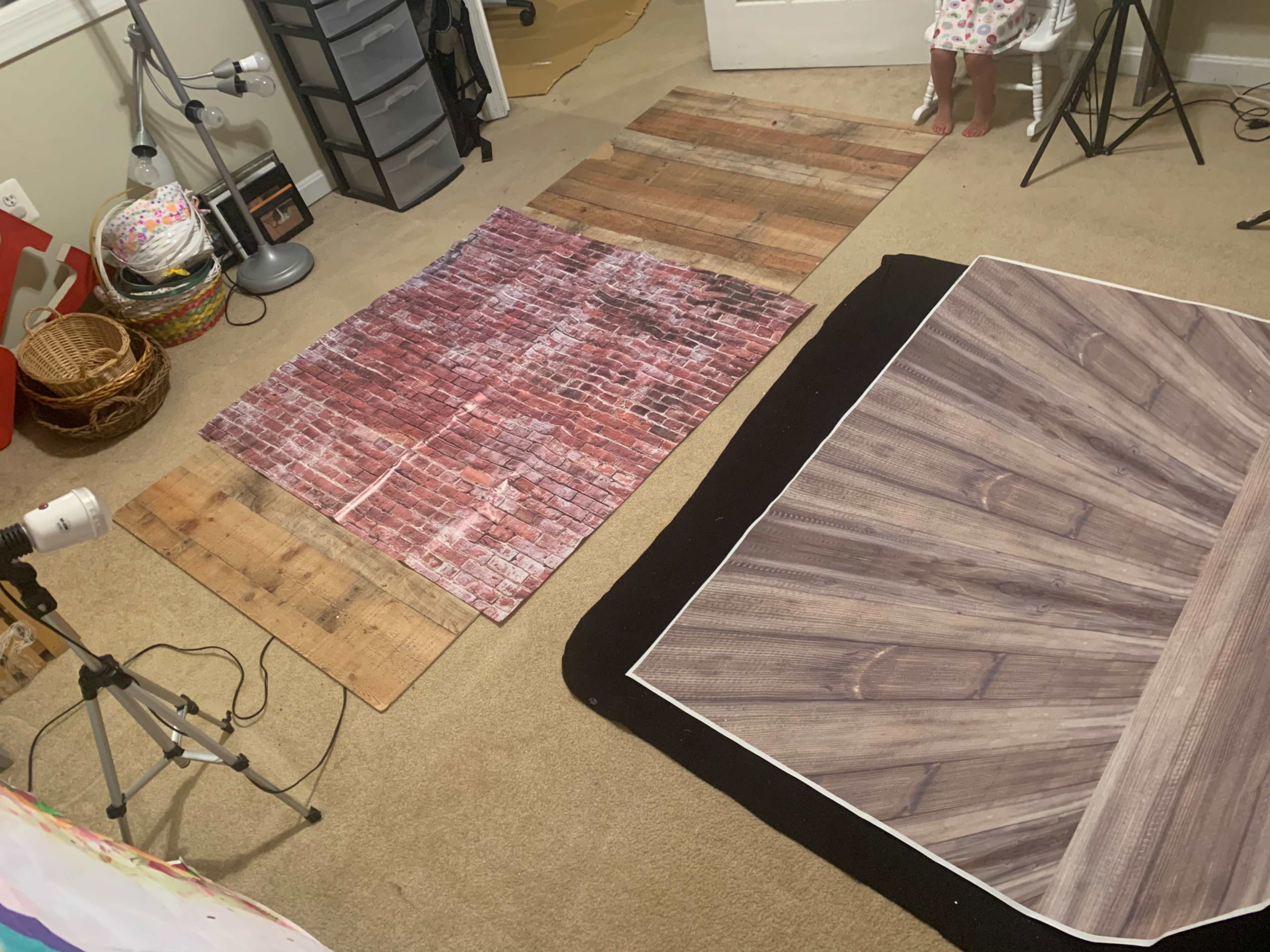 A small indoor space features multiple textured backdrops, including wooden and brick patterns, laid out on a carpeted floor.