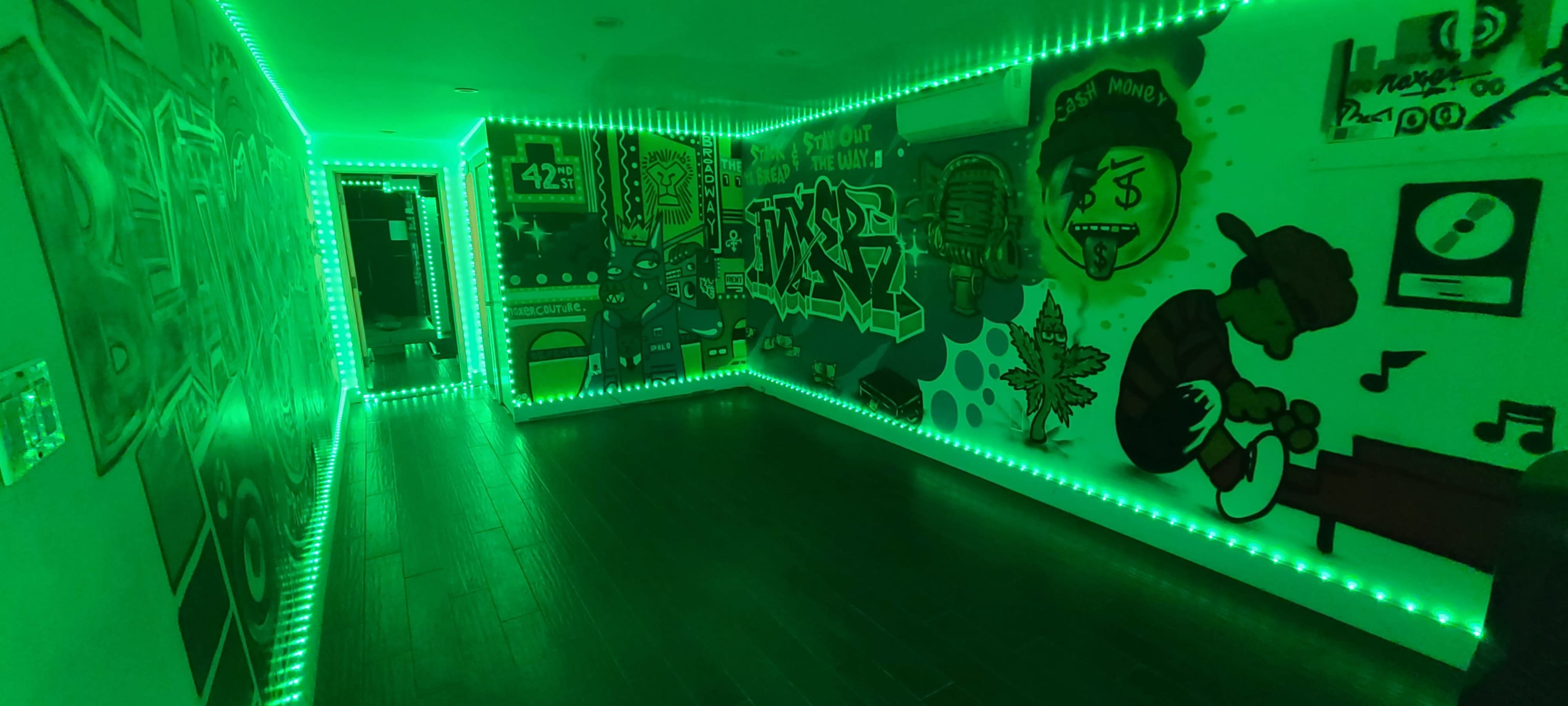 A dimly lit hallway decorated with vibrant graffiti art and illuminated by green LED lights.