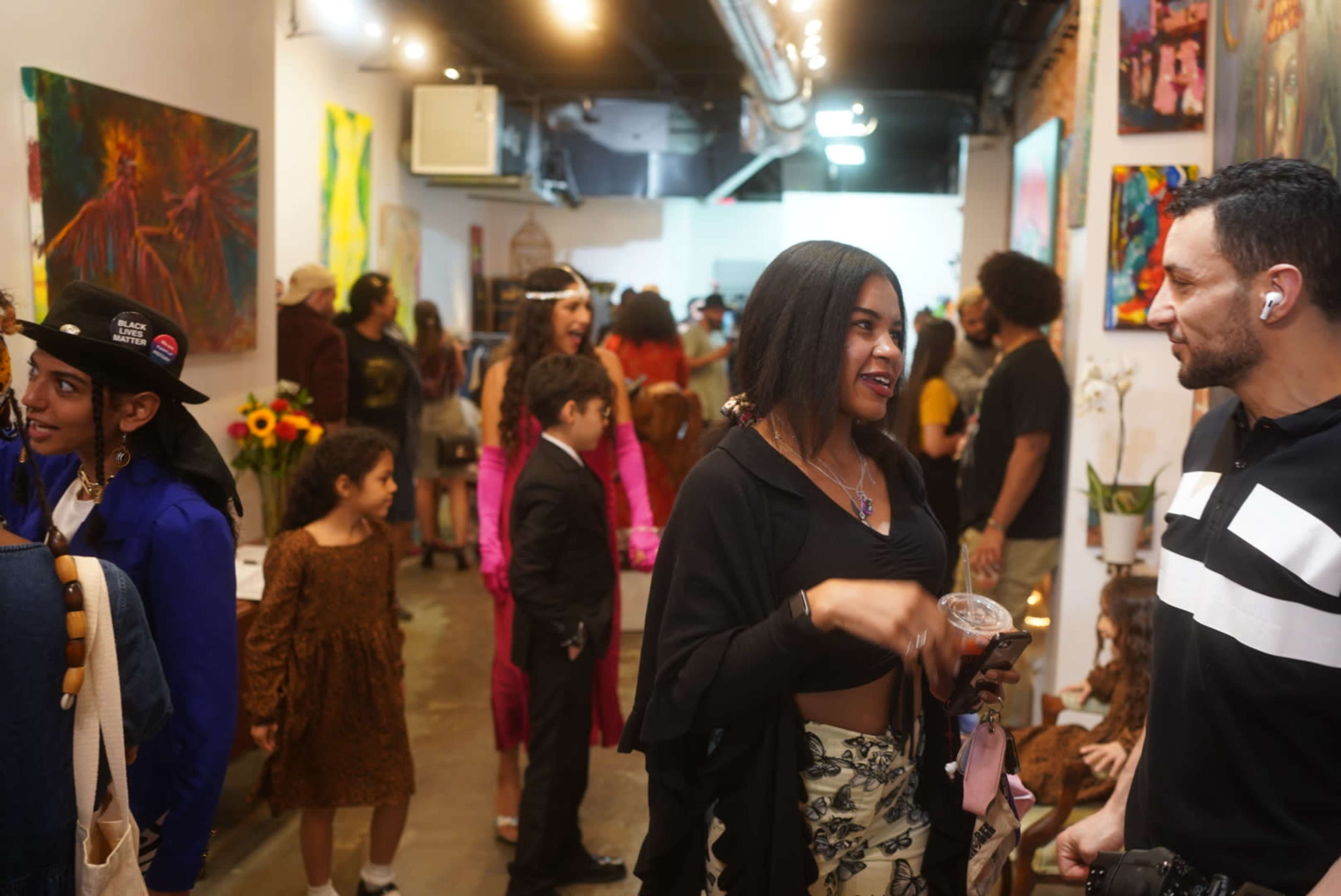A lively art gallery with people mingling, discussing artwork, and enjoying the event.