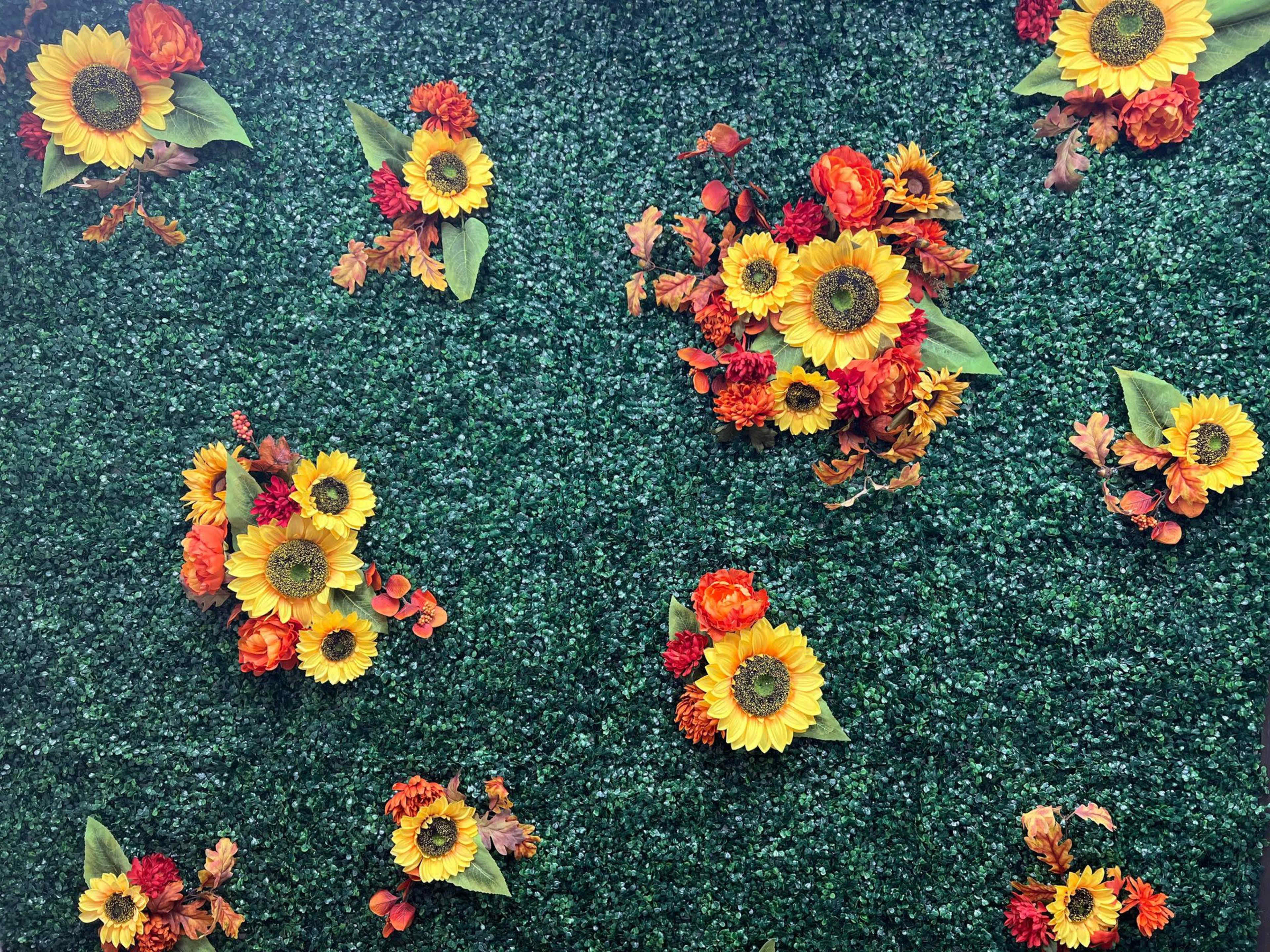 A green backdrop adorned with various sunflowers and orange flowers.
