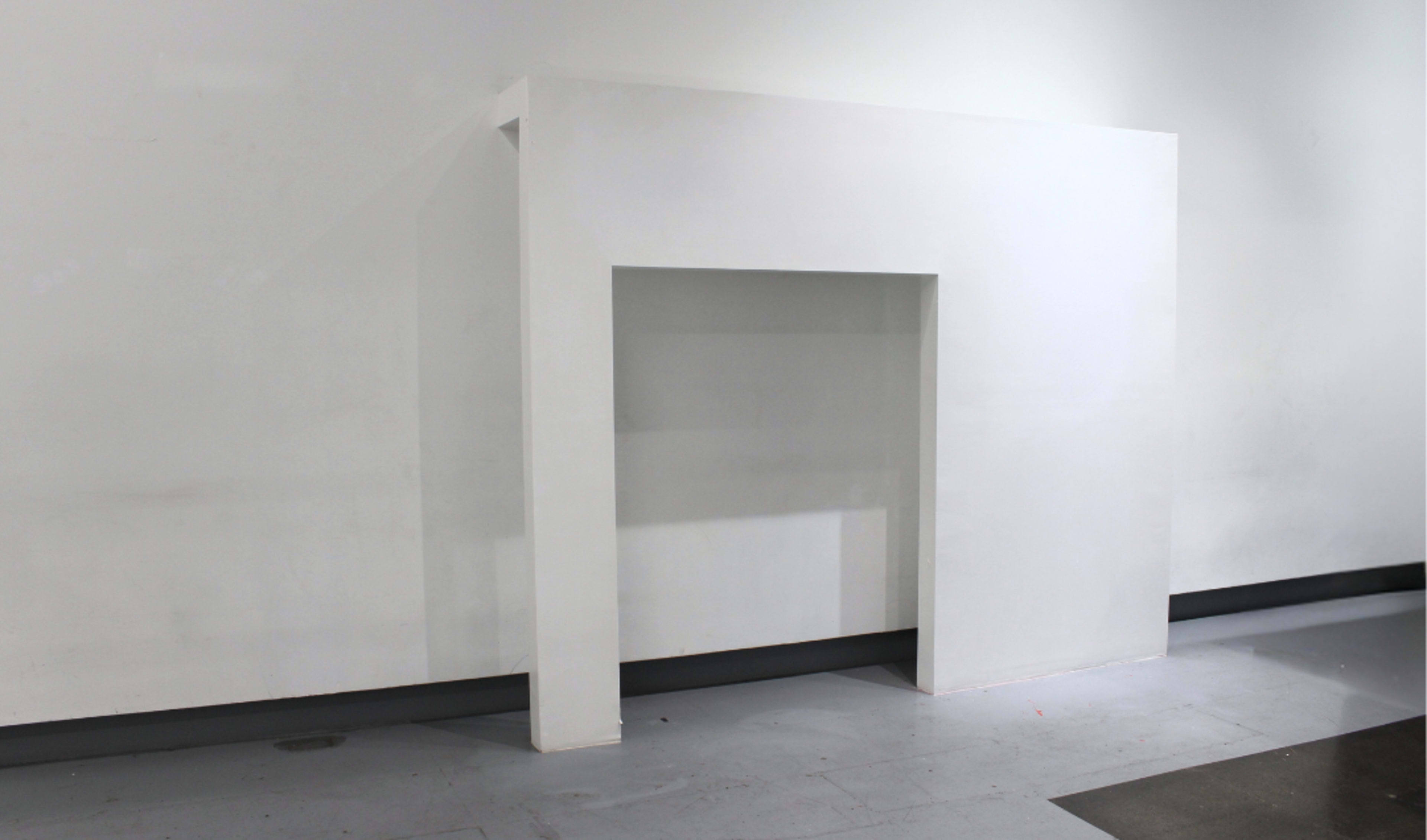 The image shows a simple, white architectural structure resembling a partial wall or niche against a plain background.