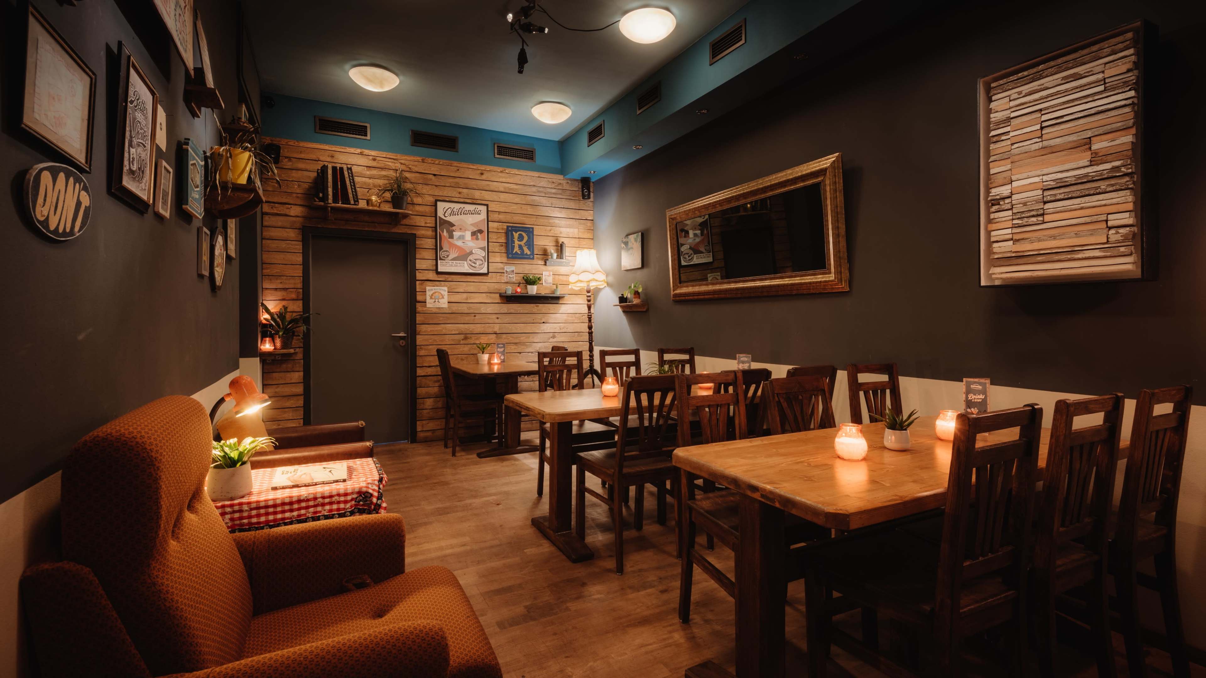 A cozy interior of a café featuring wooden tables, chairs, and a brick wall decor with a mirror and wall art.