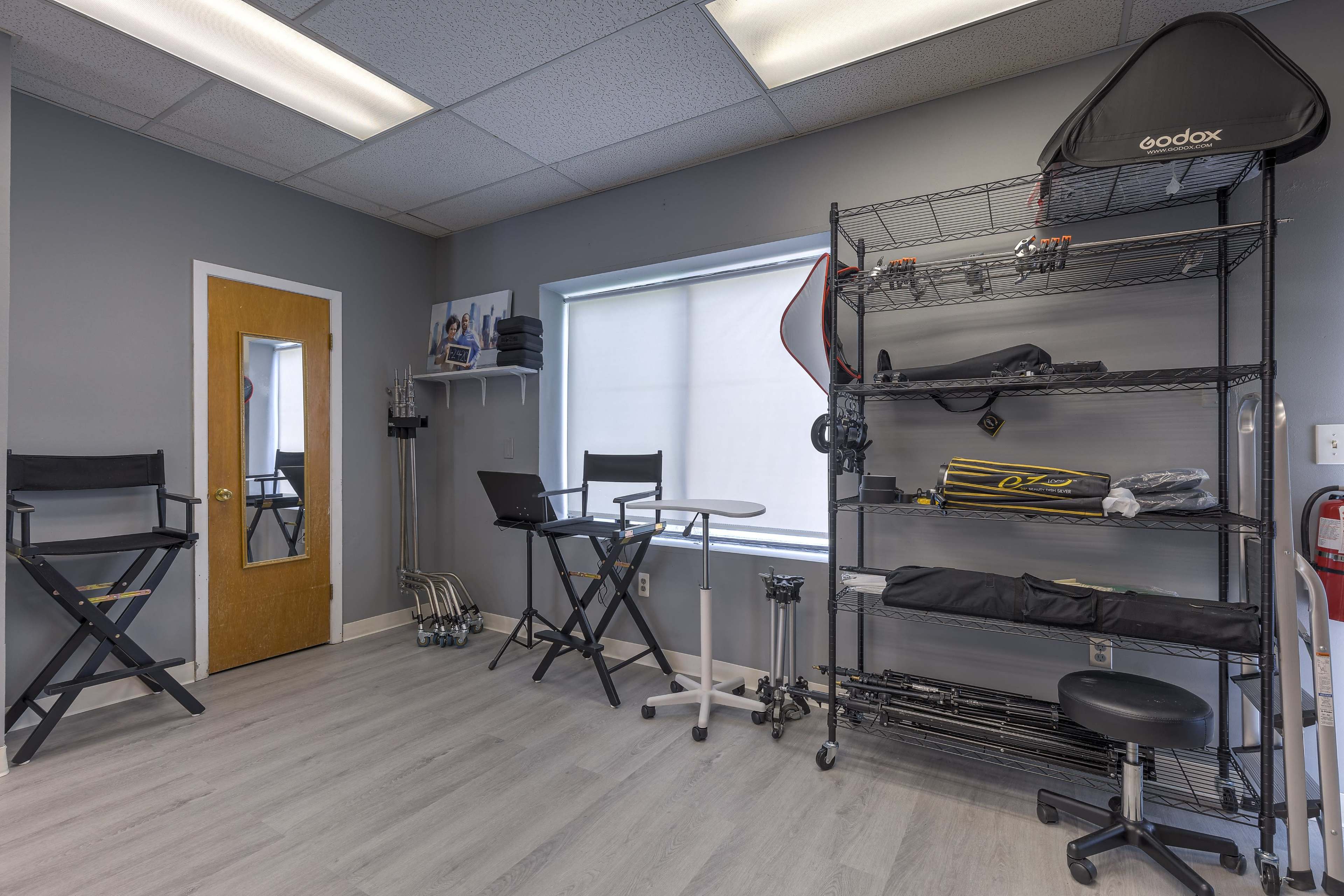 A sparsely furnished room with a mirror, storage shelves, and various equipment arranged along the walls.