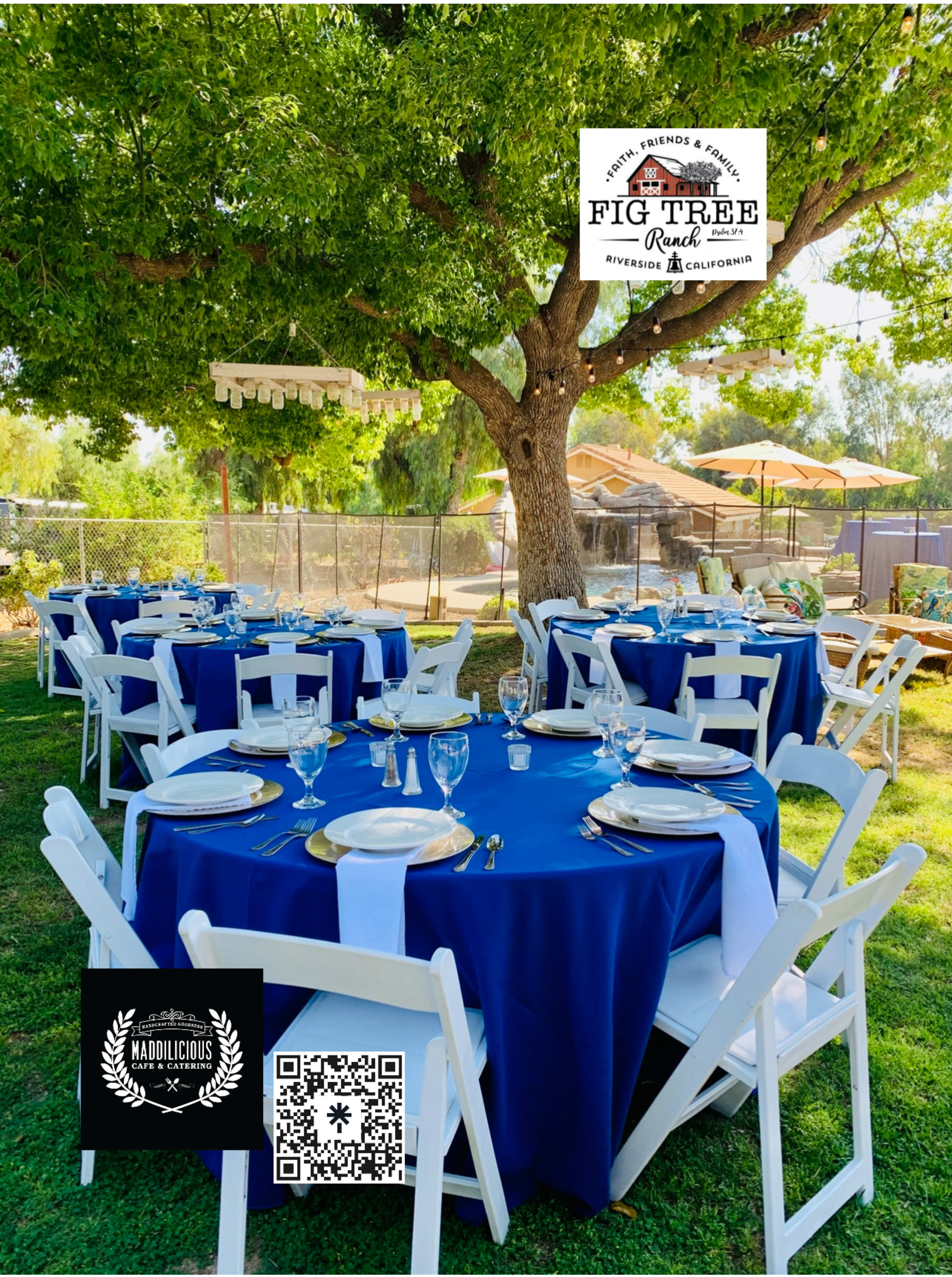 The image shows an outdoor dining setup with blue tablecloths and white chair covers arranged under a large tree, accompanied by decorative elements and logos.