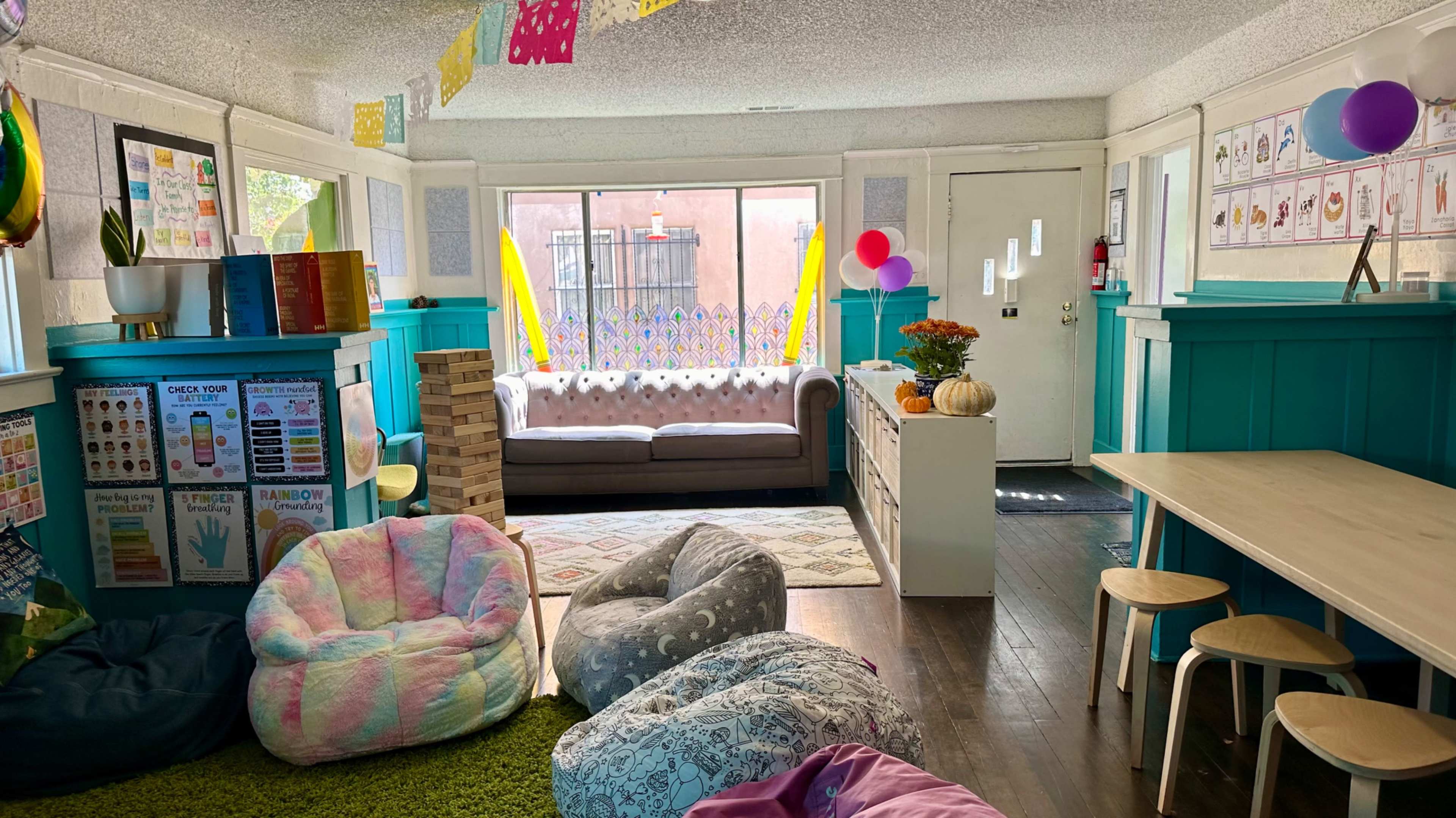 The image shows a colorful, cozy interior space with bean bags, a couch, and decorations, designed for a community or recreational area.