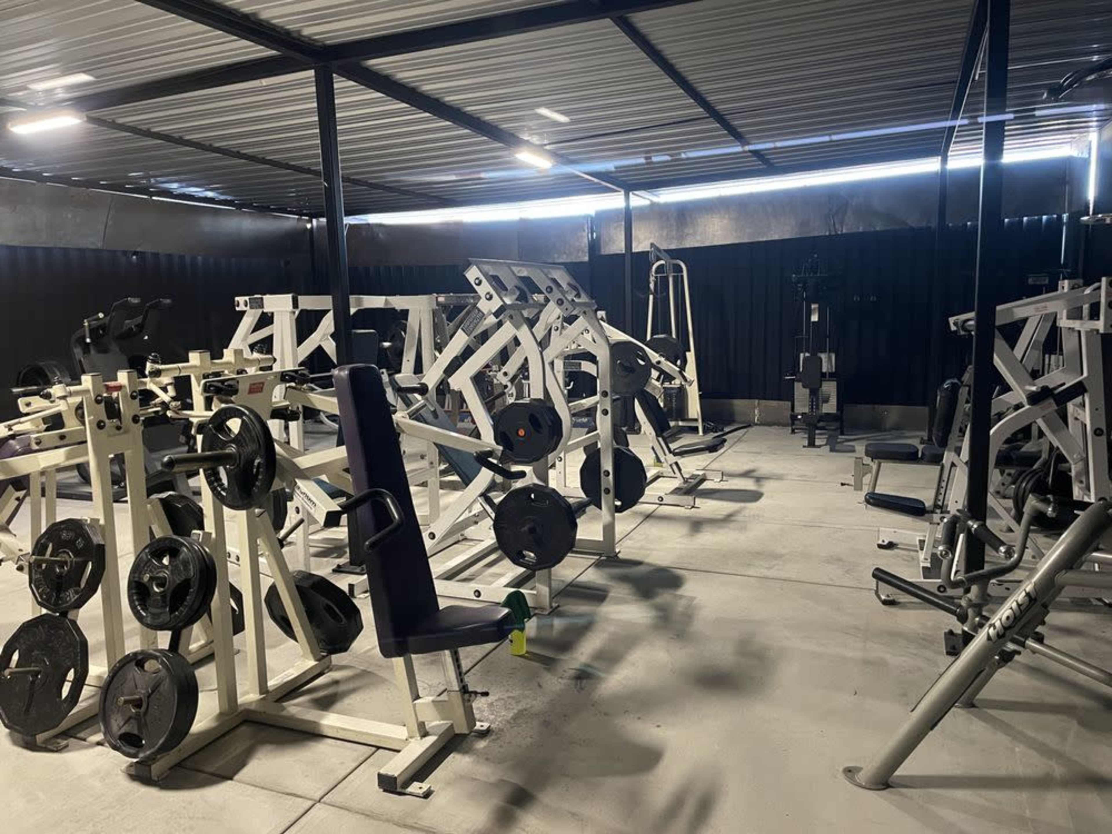 A gym with various weightlifting machines and free weights arranged throughout the space.