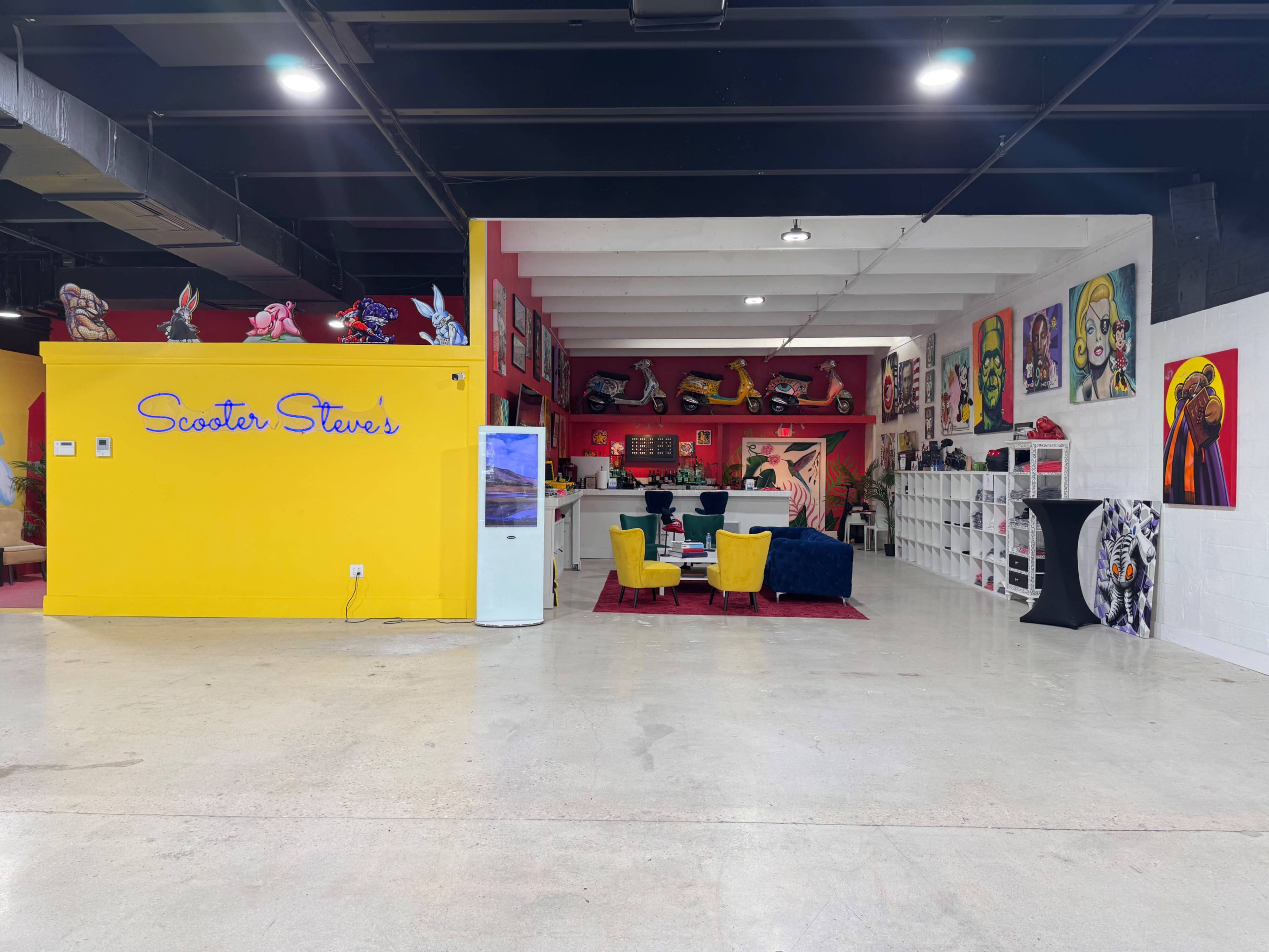An indoor space labeled "Scooter Steve's," featuring colorful seating arrangements, art on the walls, and a reception area with a display refrigerator.