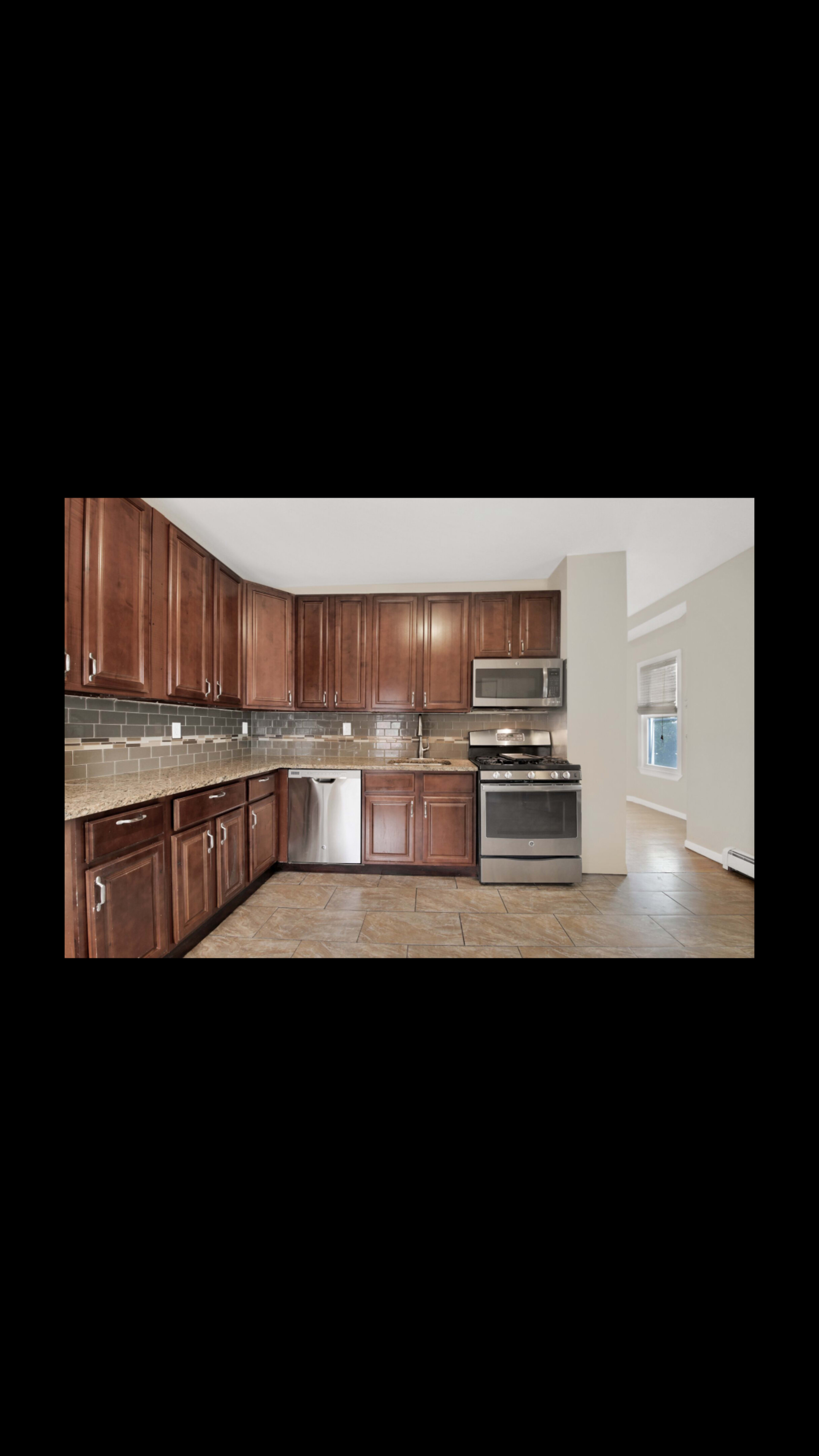 The image shows a kitchen with dark wooden cabinets, stainless steel appliances, and beige tiled flooring.