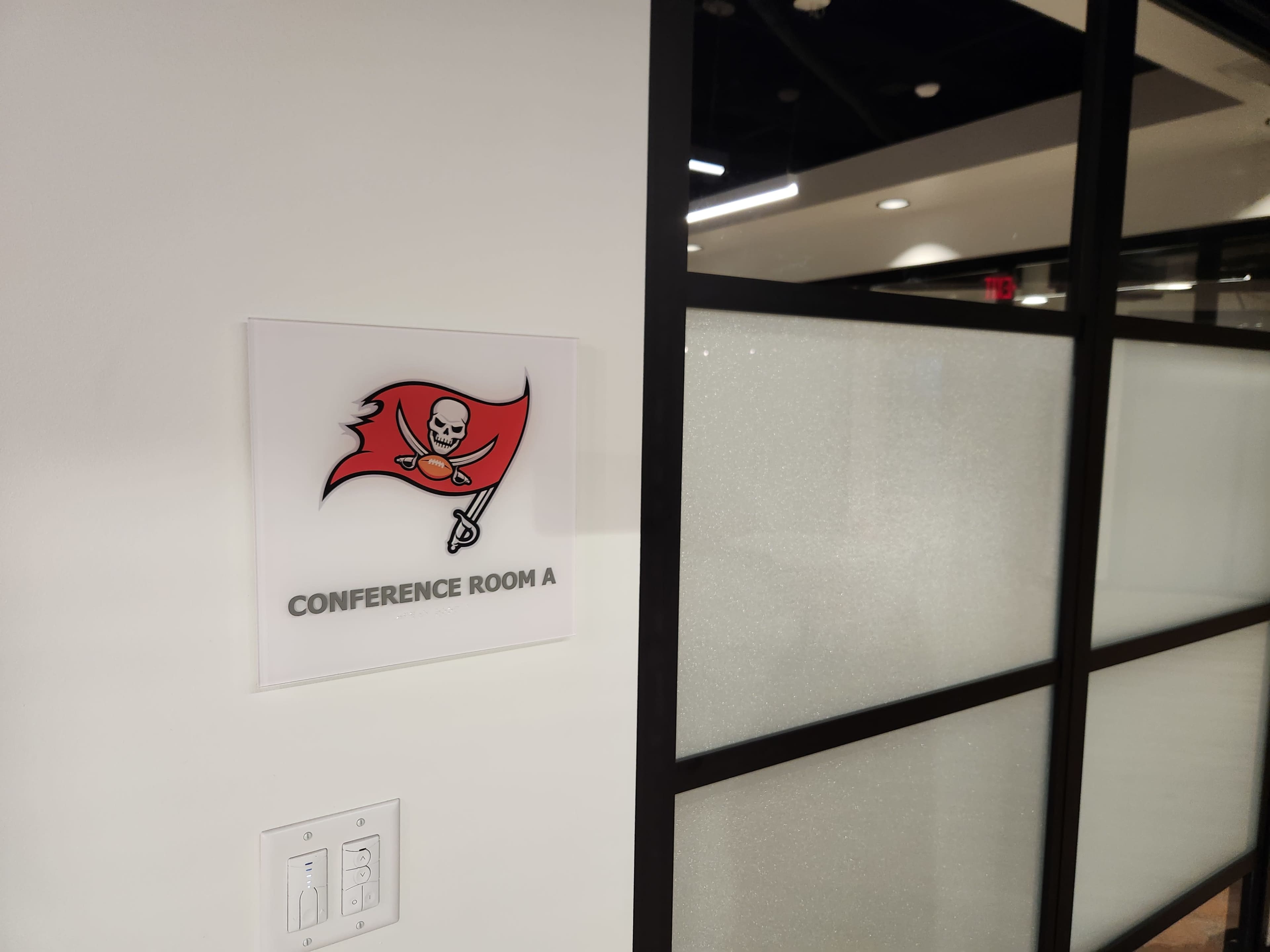 A sign indicating "Conference Room A" features a pirate-themed logo on a glass wall.