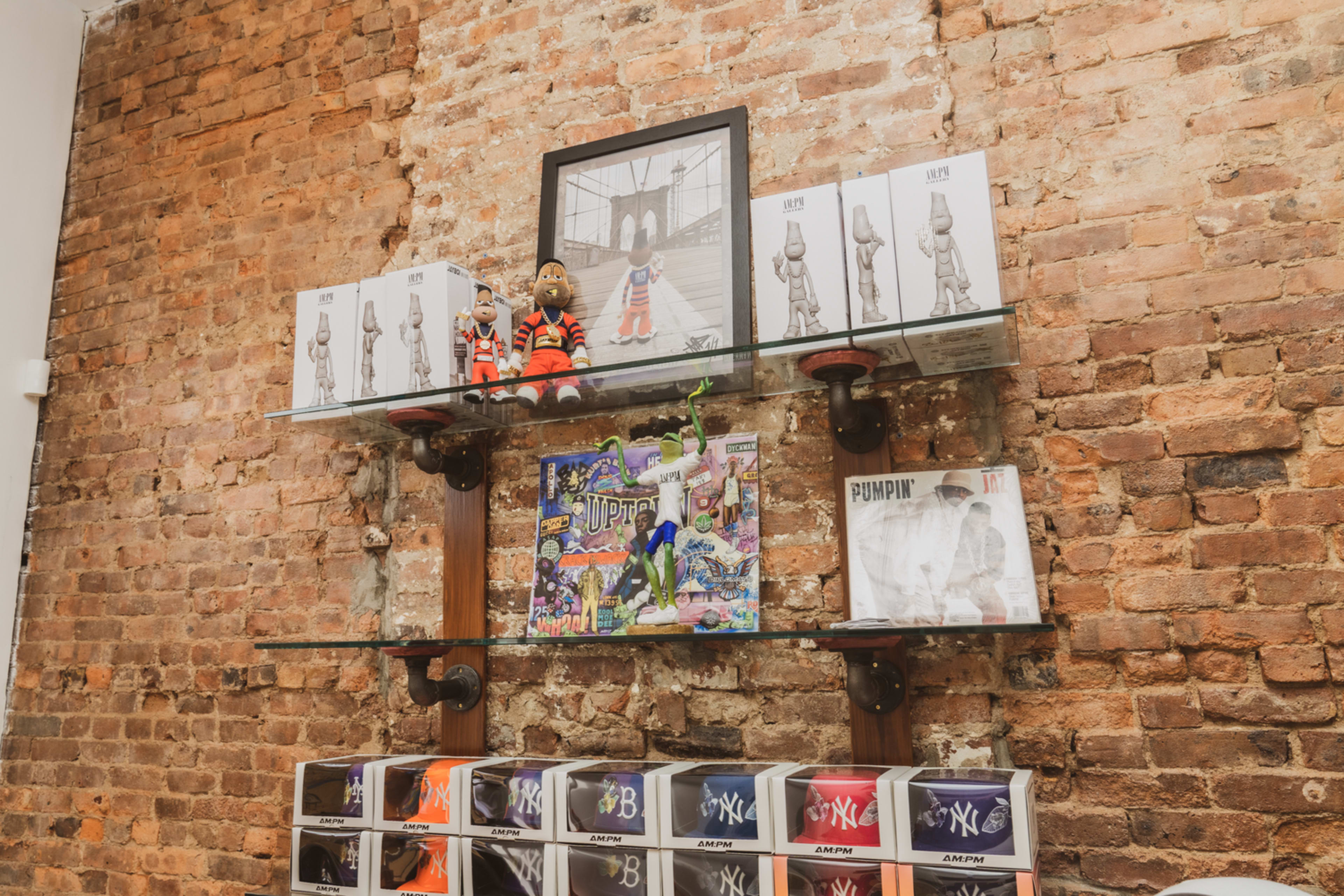 A display shelf features merchandise, including figurines, artwork, and vinyl records, against a brick wall backdrop.