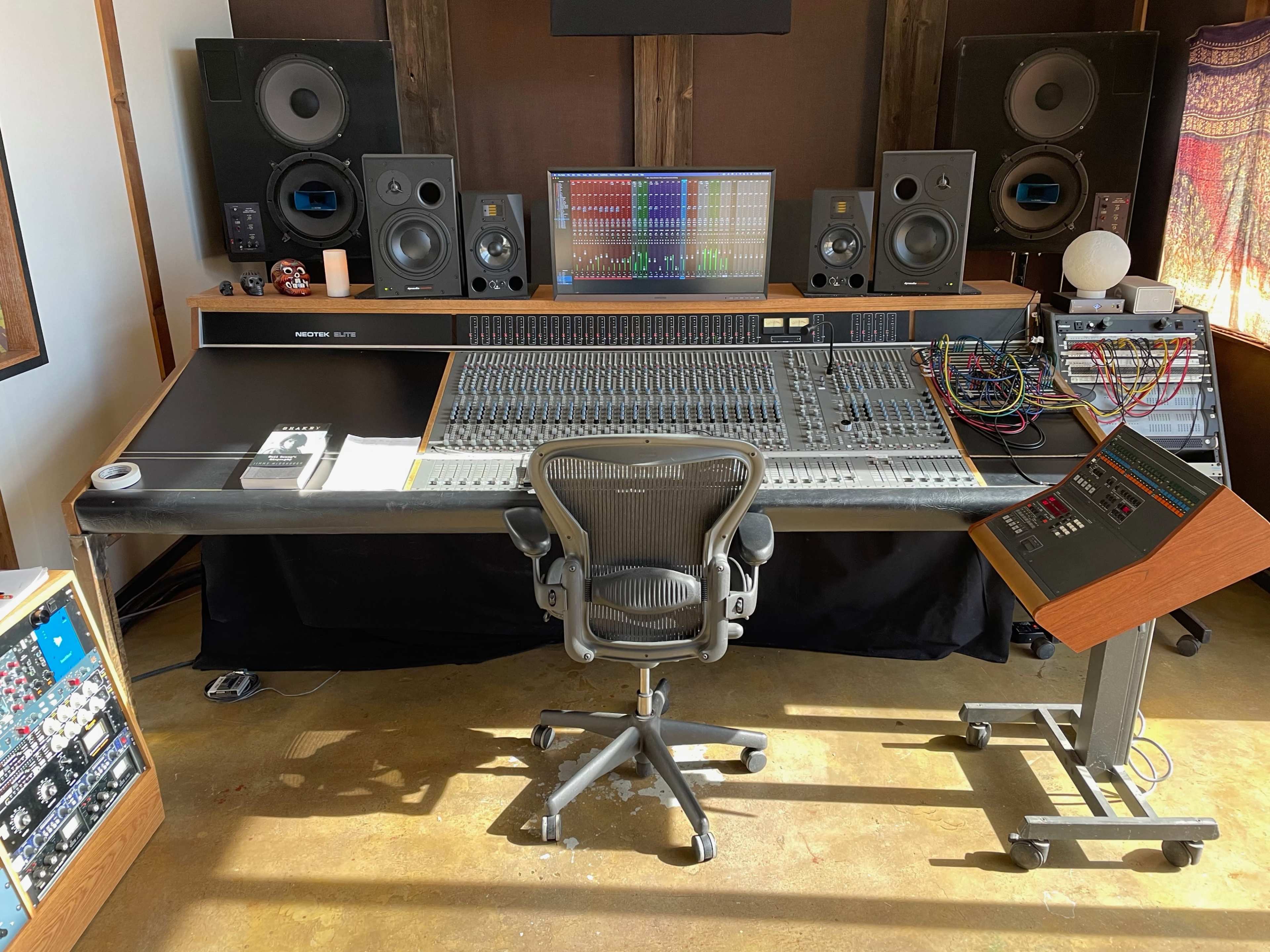 A professional audio mixing studio with a large mixing console, speakers, and various audio equipment.