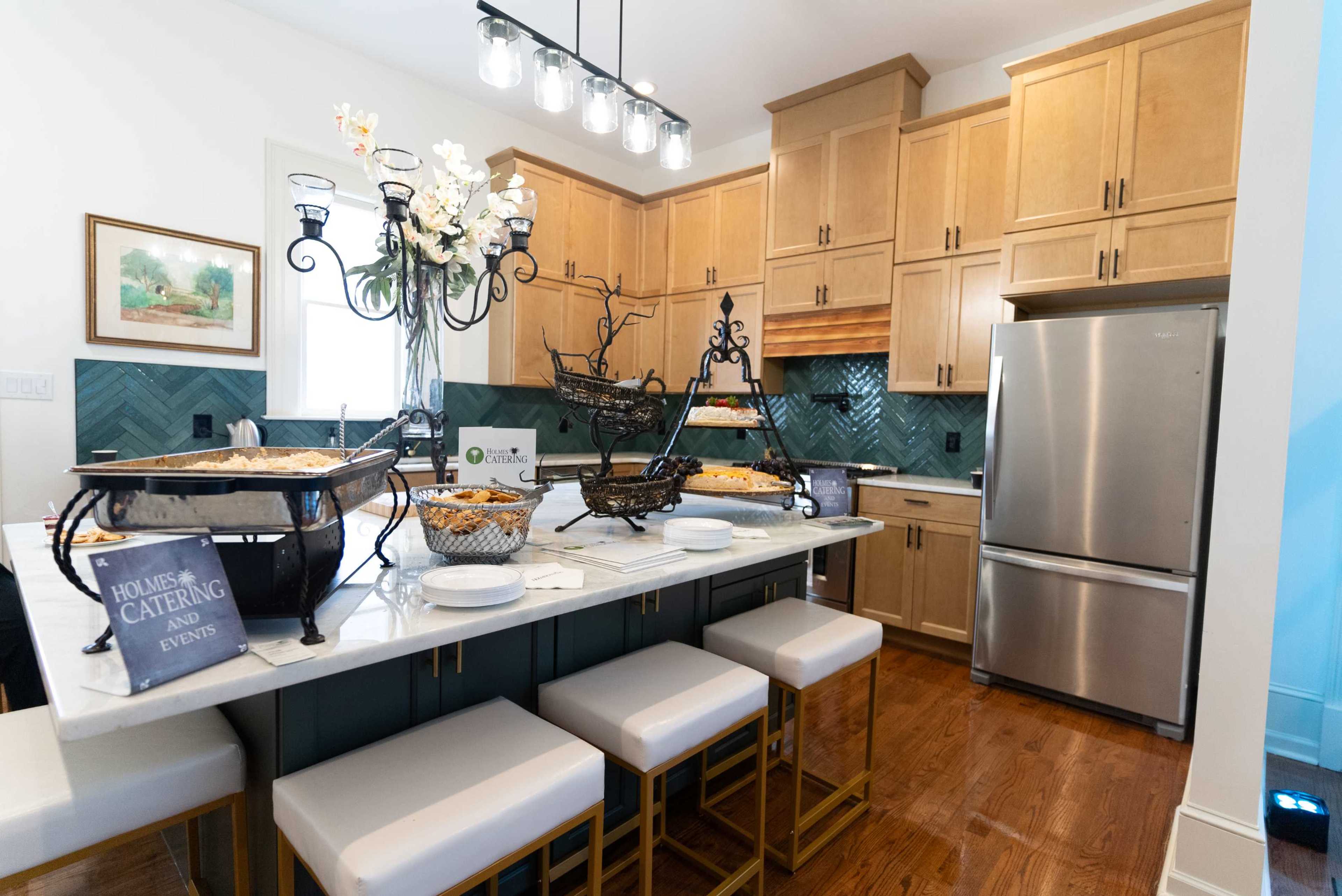 A modern kitchen features wooden cabinetry, a marble island with seating, and stainless steel appliances.