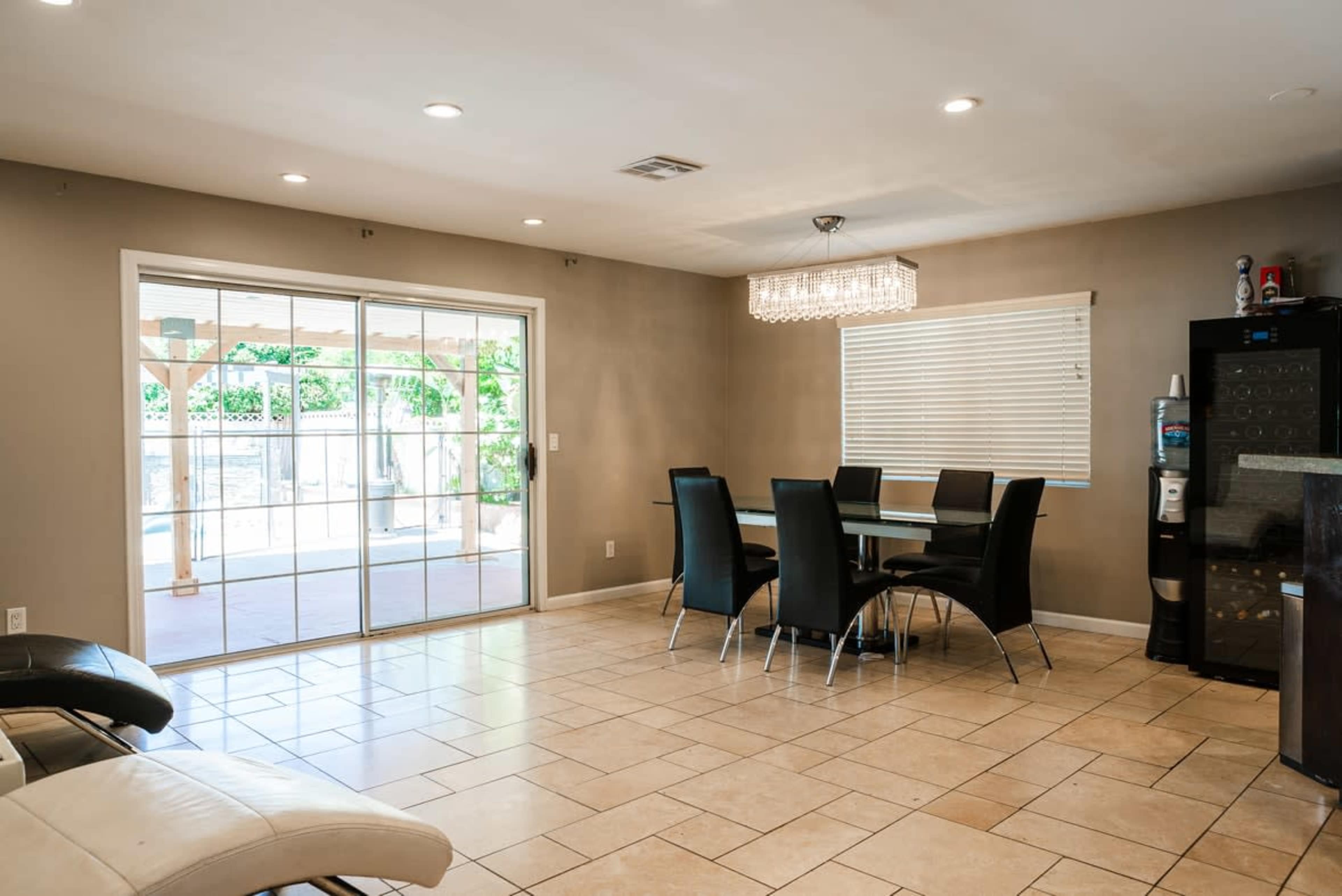 A dining area features a glass table surrounded by black chairs, with a sliding glass door leading to an outdoor space.