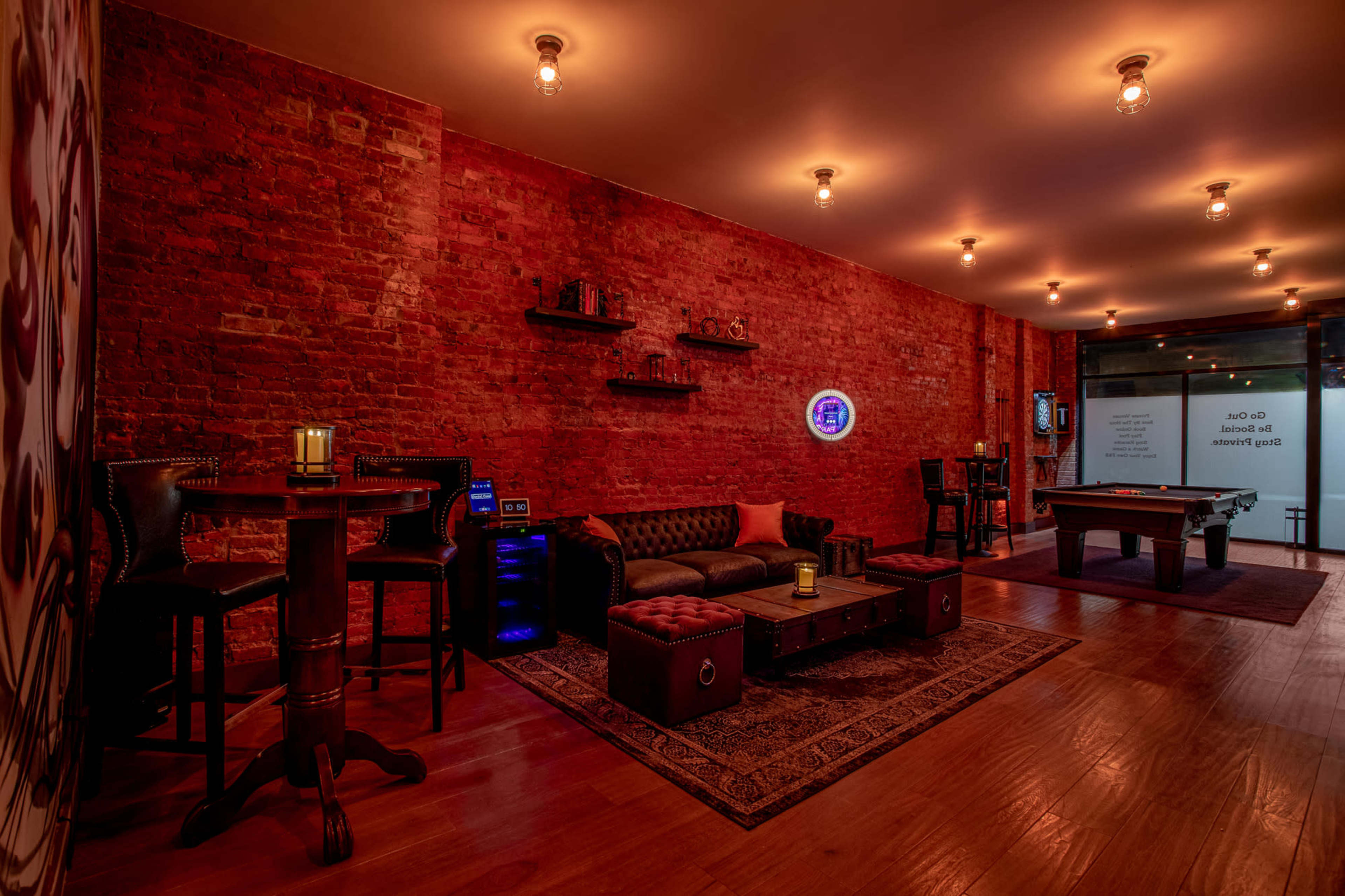The image shows a modern lounge area with exposed brick walls, ambient lighting, a pool table, and various seating arrangements.