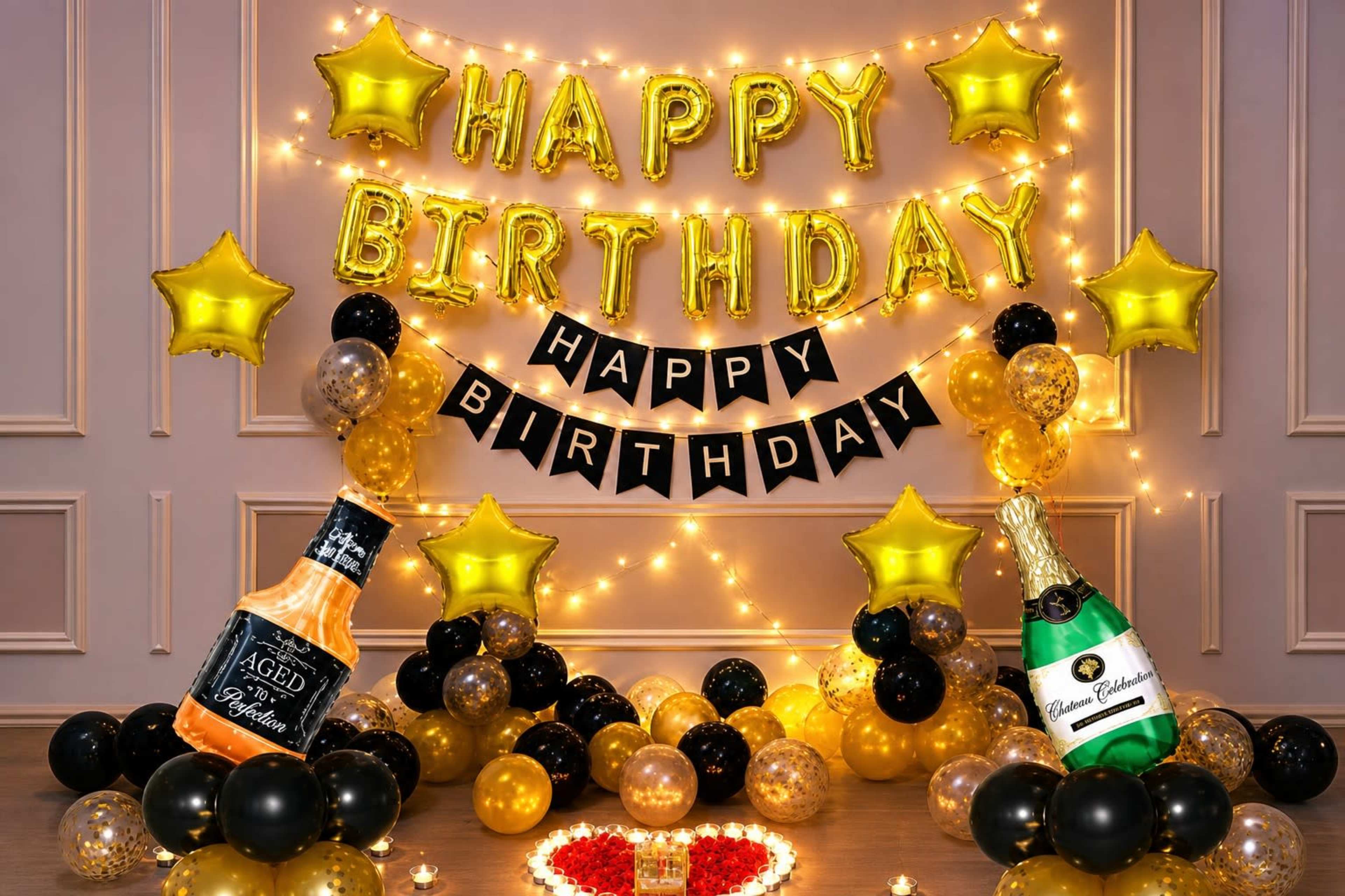 The scene features a festive birthday decoration with gold balloons, black and gold stars, a "Happy Birthday" banner, and two bottles of champagne surrounded by a heart made of flowers.