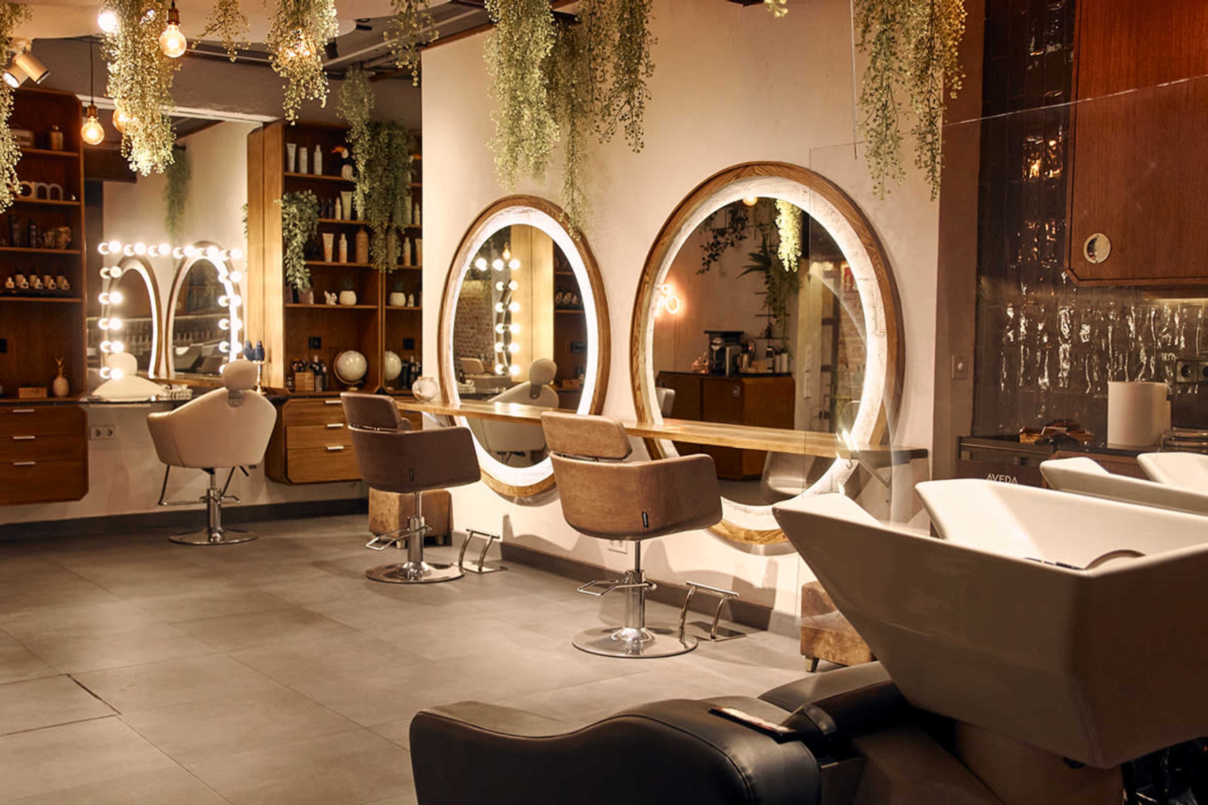 The image shows a modern salon interior with circular mirrors, stylish chairs, and well-organized shelves containing hair products.