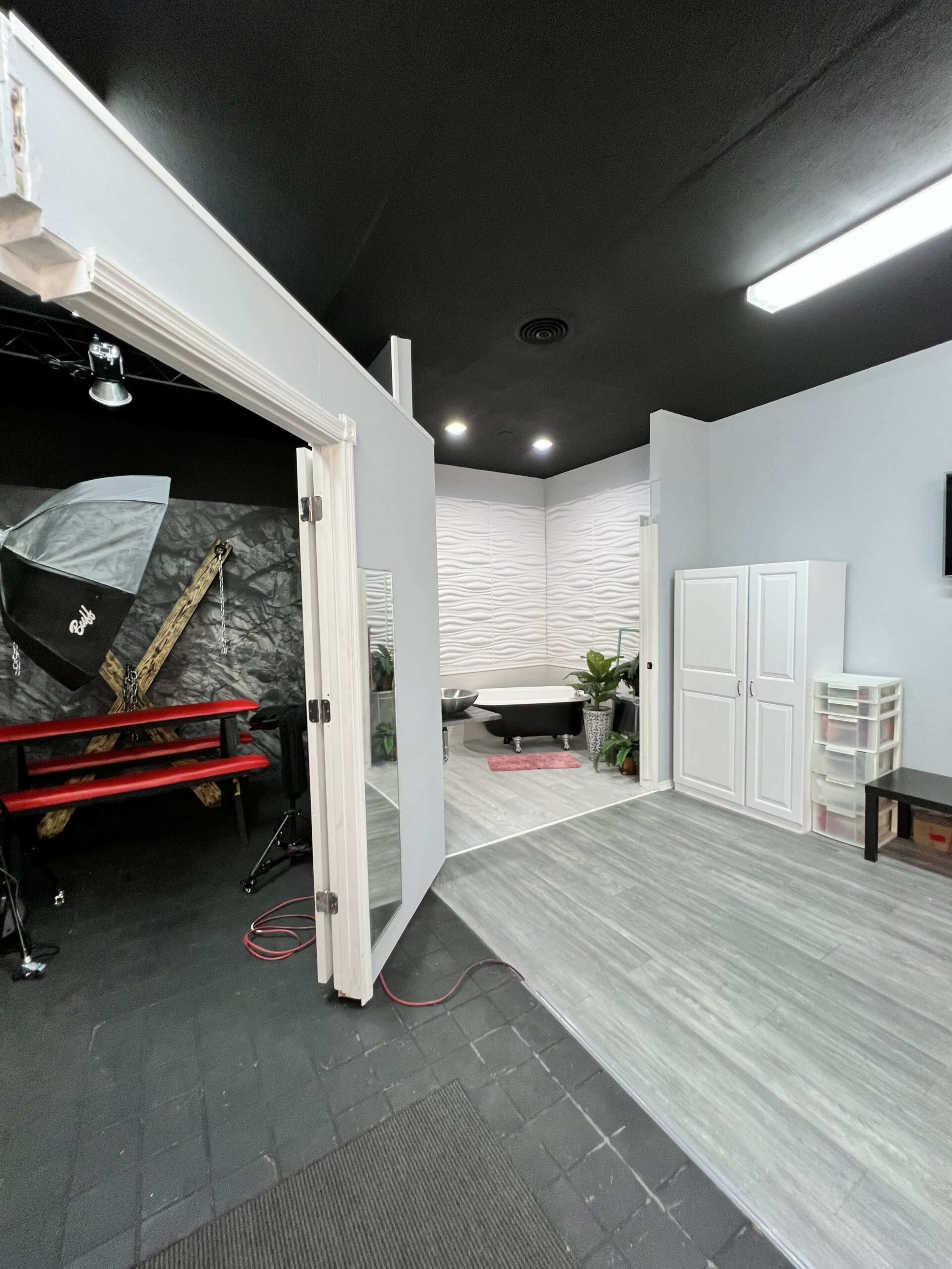 The image shows a modern studio space with a photo backdrop, a wardrobe, and a varied flooring layout.