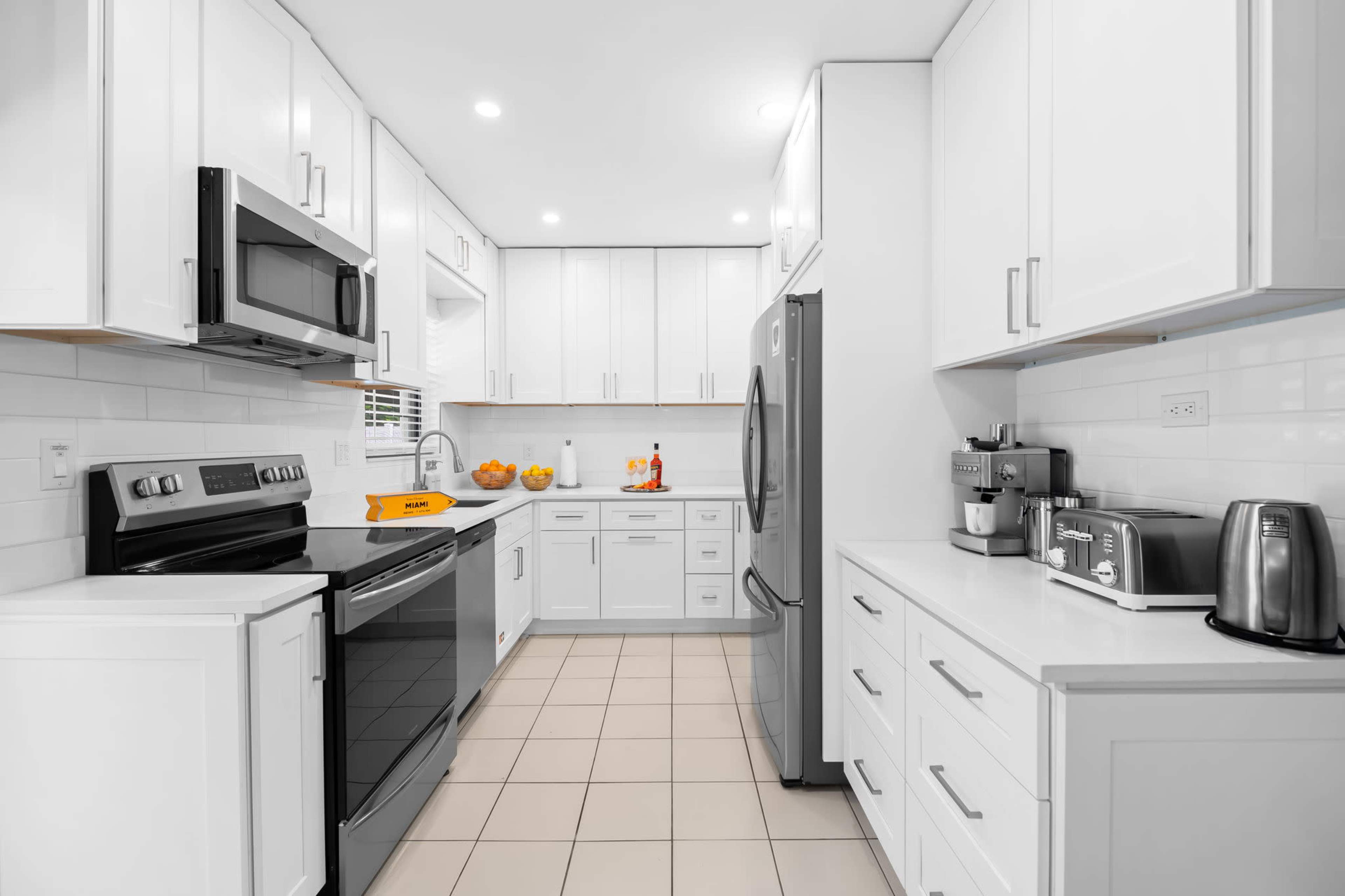 The image shows a modern kitchen with white cabinetry, stainless steel appliances, and a tiled floor.