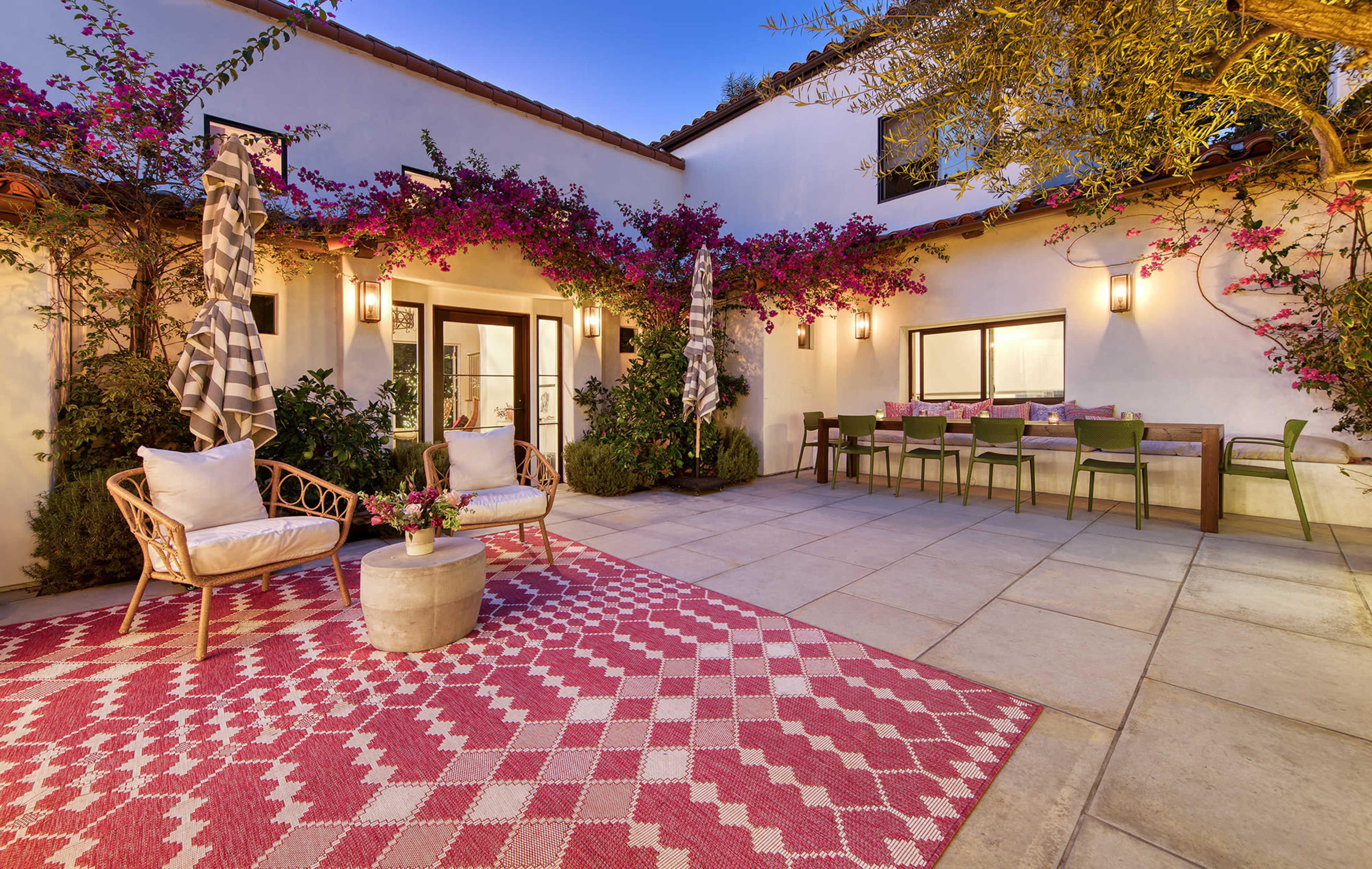 The scene shows a patio area with seating, a small table, and vibrant bougainvillea plants along the walls.