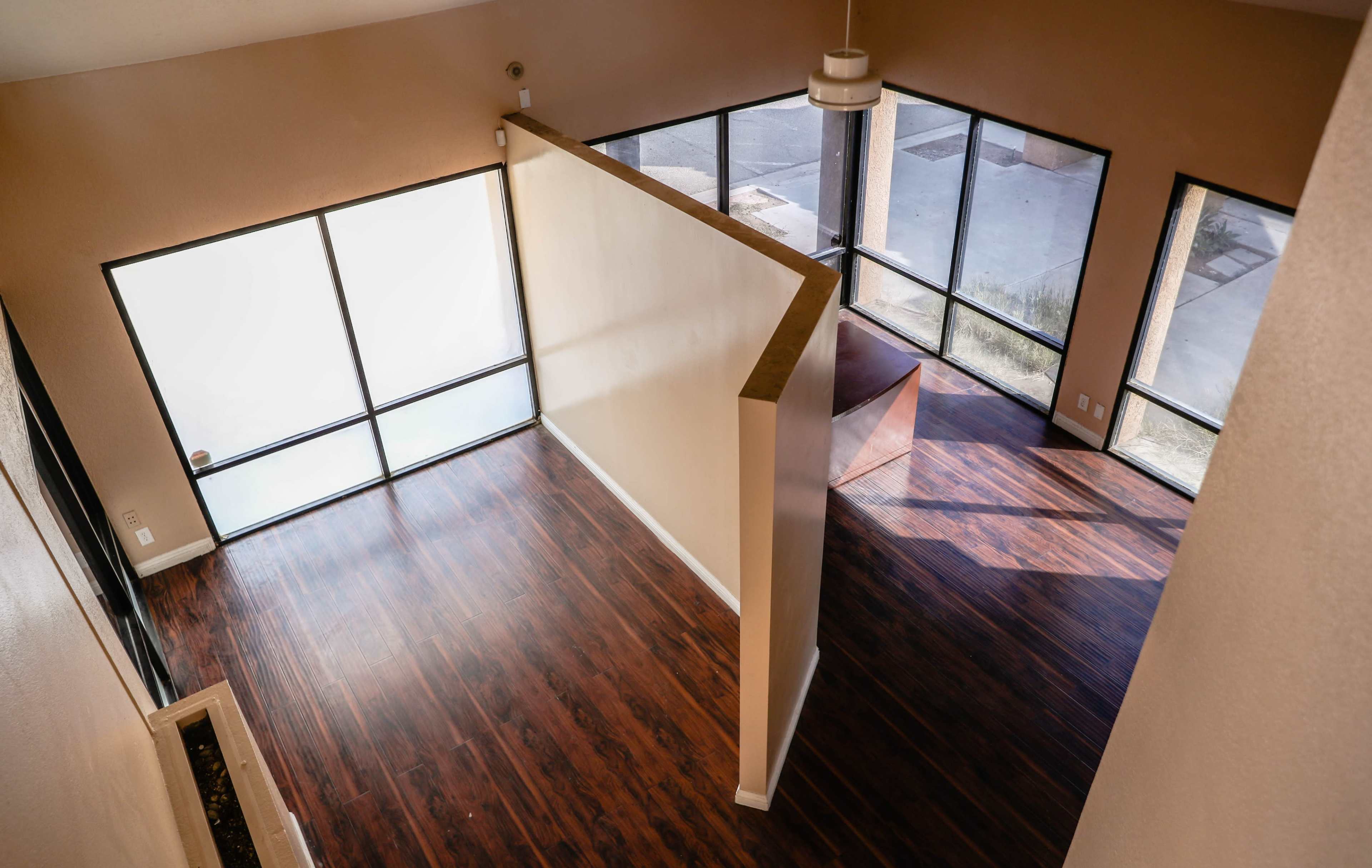 A spacious interior of a home with large windows and polished dark wood flooring.