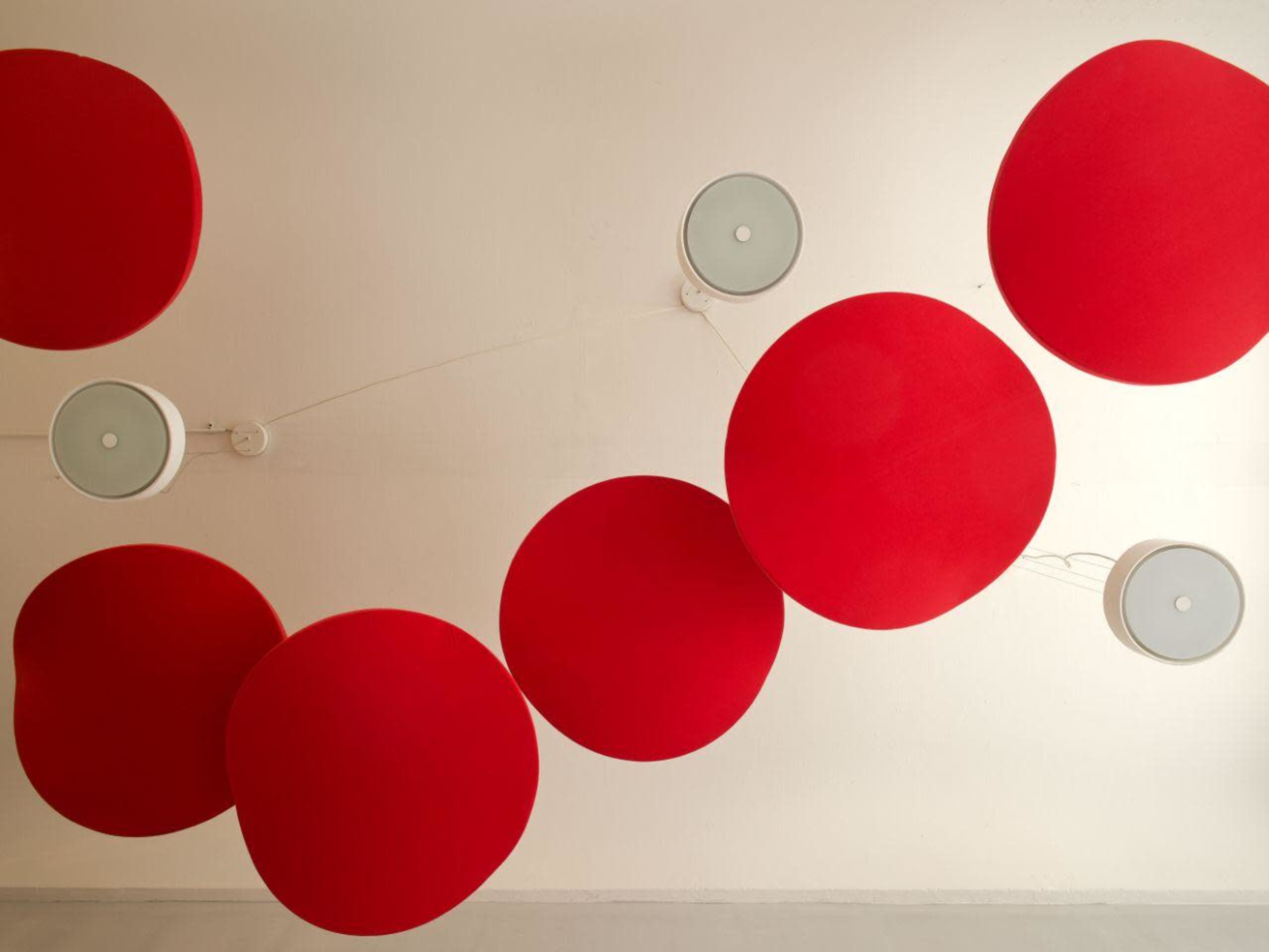 The image shows a ceiling with large red circular decorations and light fixtures arranged in an abstract pattern.