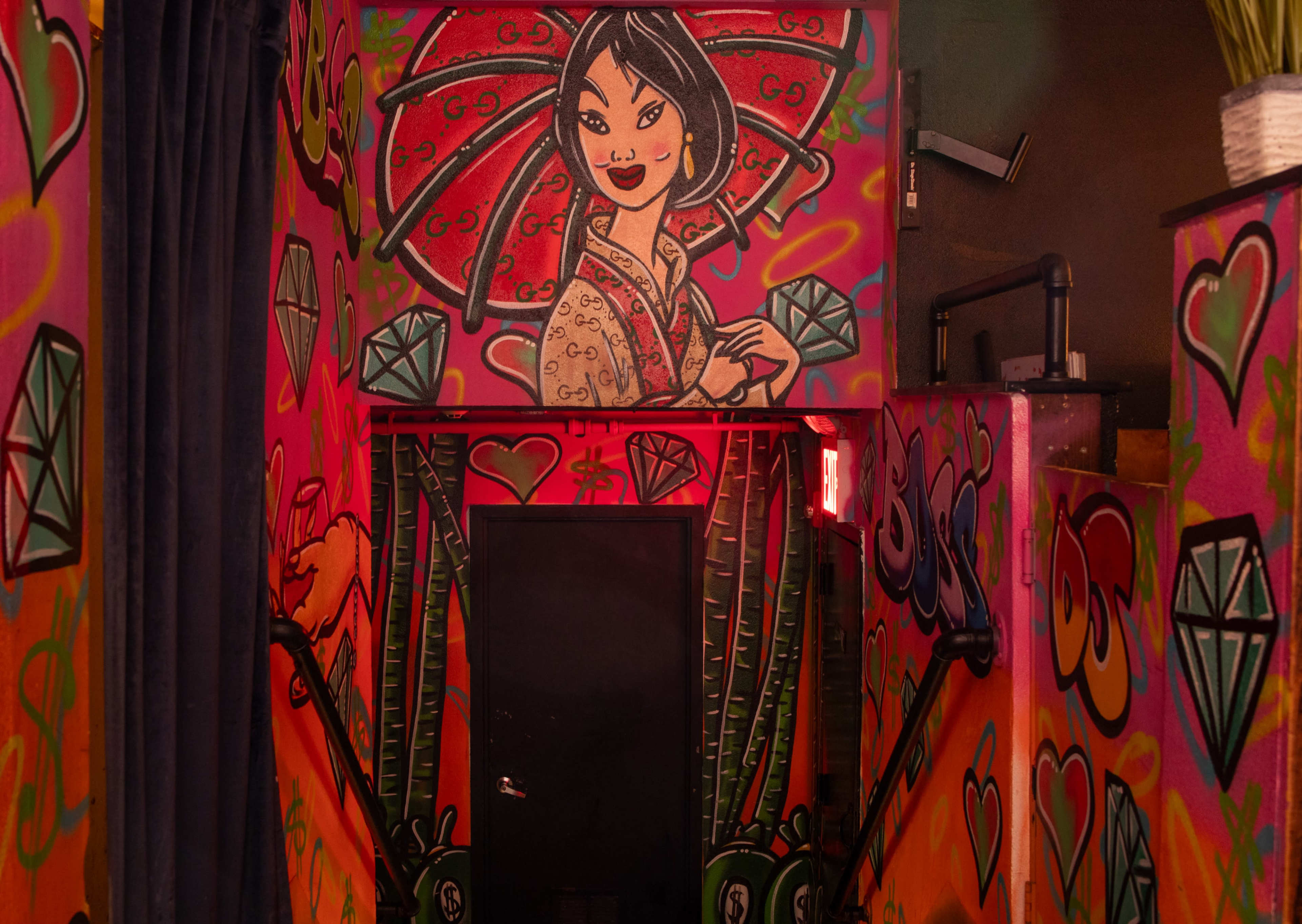The image shows a colorful staircase adorned with vibrant graffiti, including a depiction of a woman holding a red umbrella and various decorative elements like diamonds and bamboo.