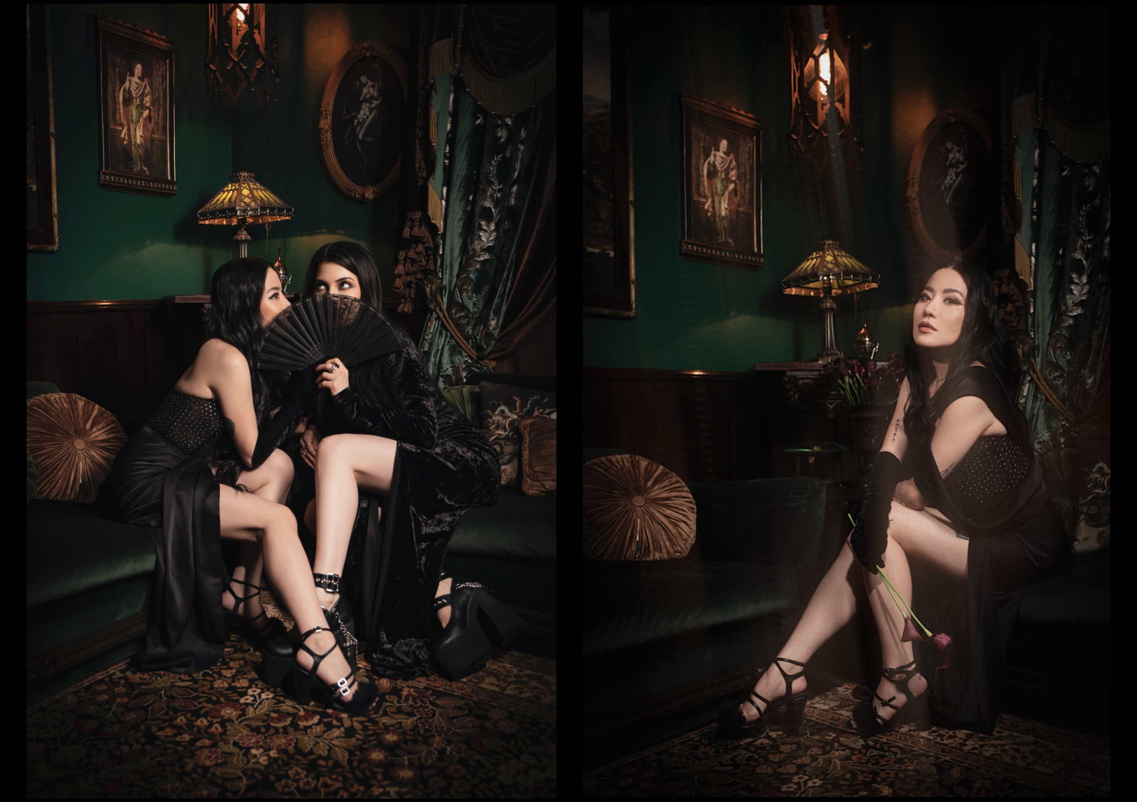 Two women in dark, elegant attire pose in a lavishly decorated room, one hiding behind a fan while the other sits with a rose.