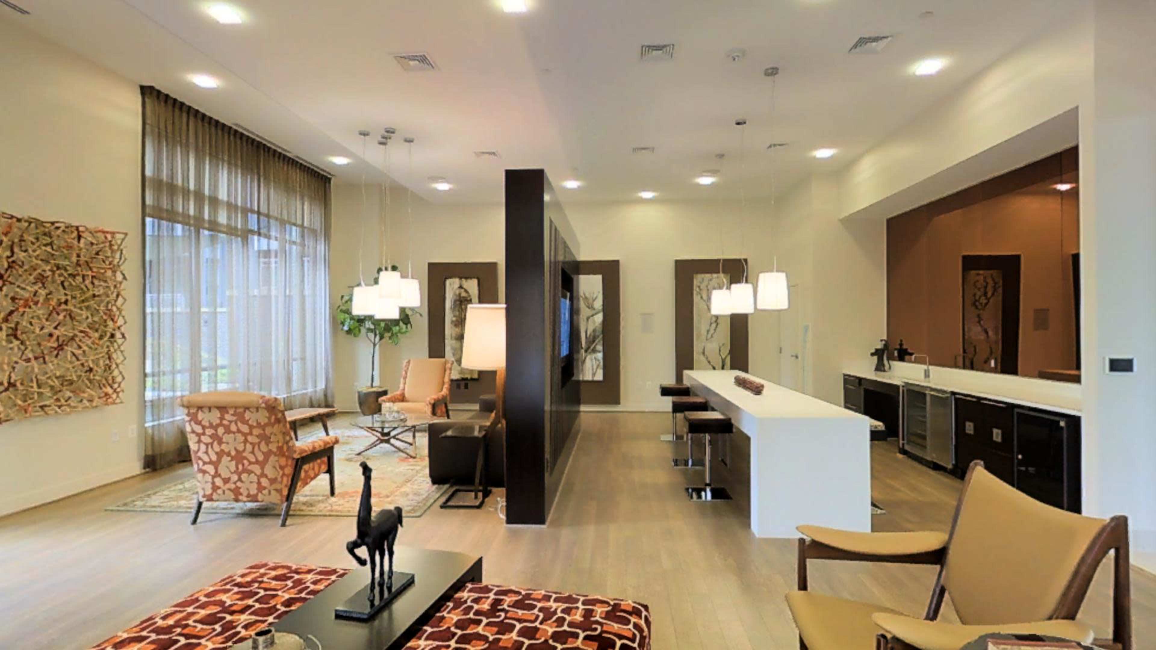 A modern, open-concept living space with a kitchen, dining area, and seating arrangement featuring contemporary furniture and artwork.