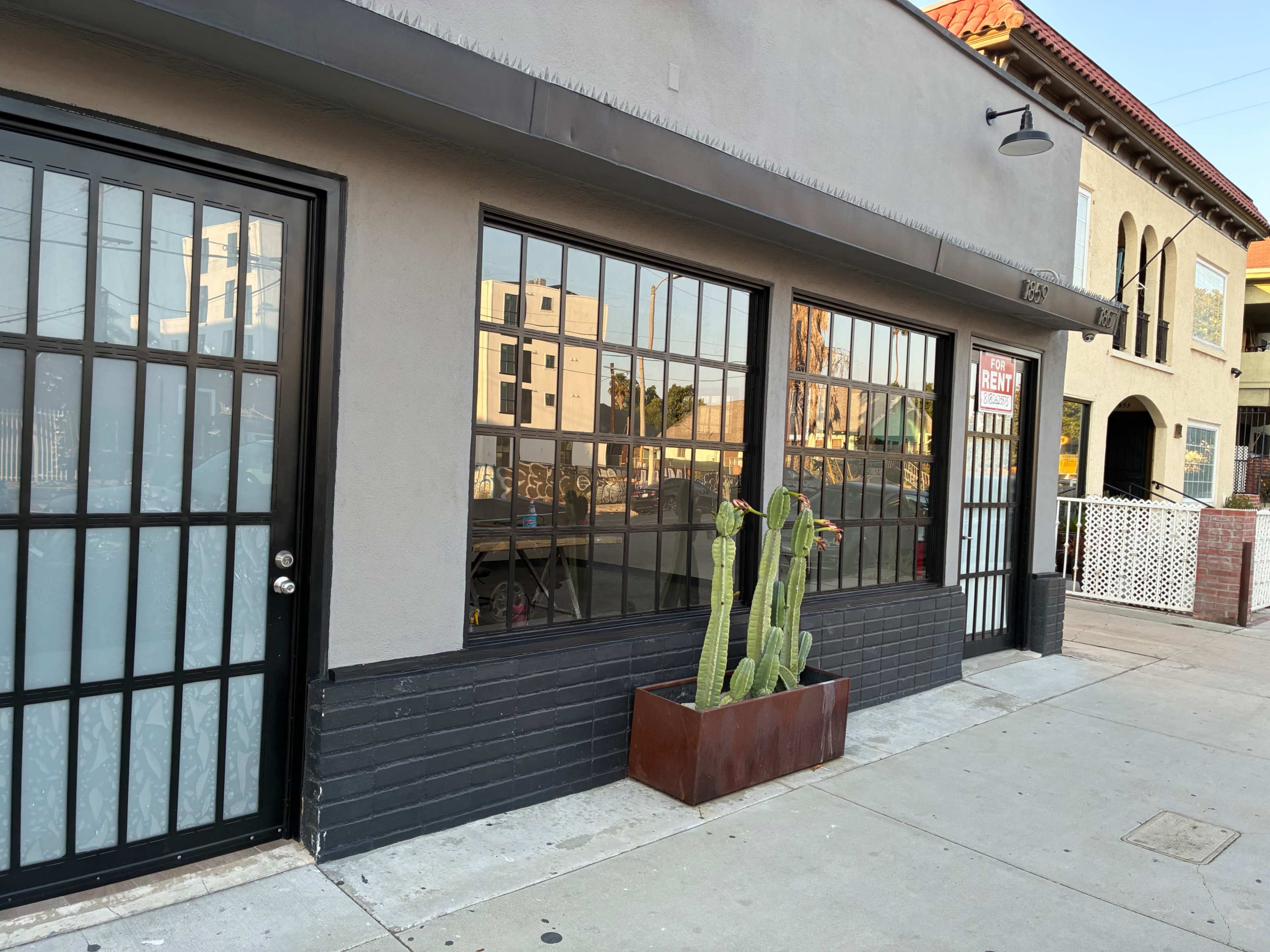 Empty modern storefront commercial space with concrete floors, large custom steel windows and oversized door. Image in South Los Angeles, Los Angeles, CA