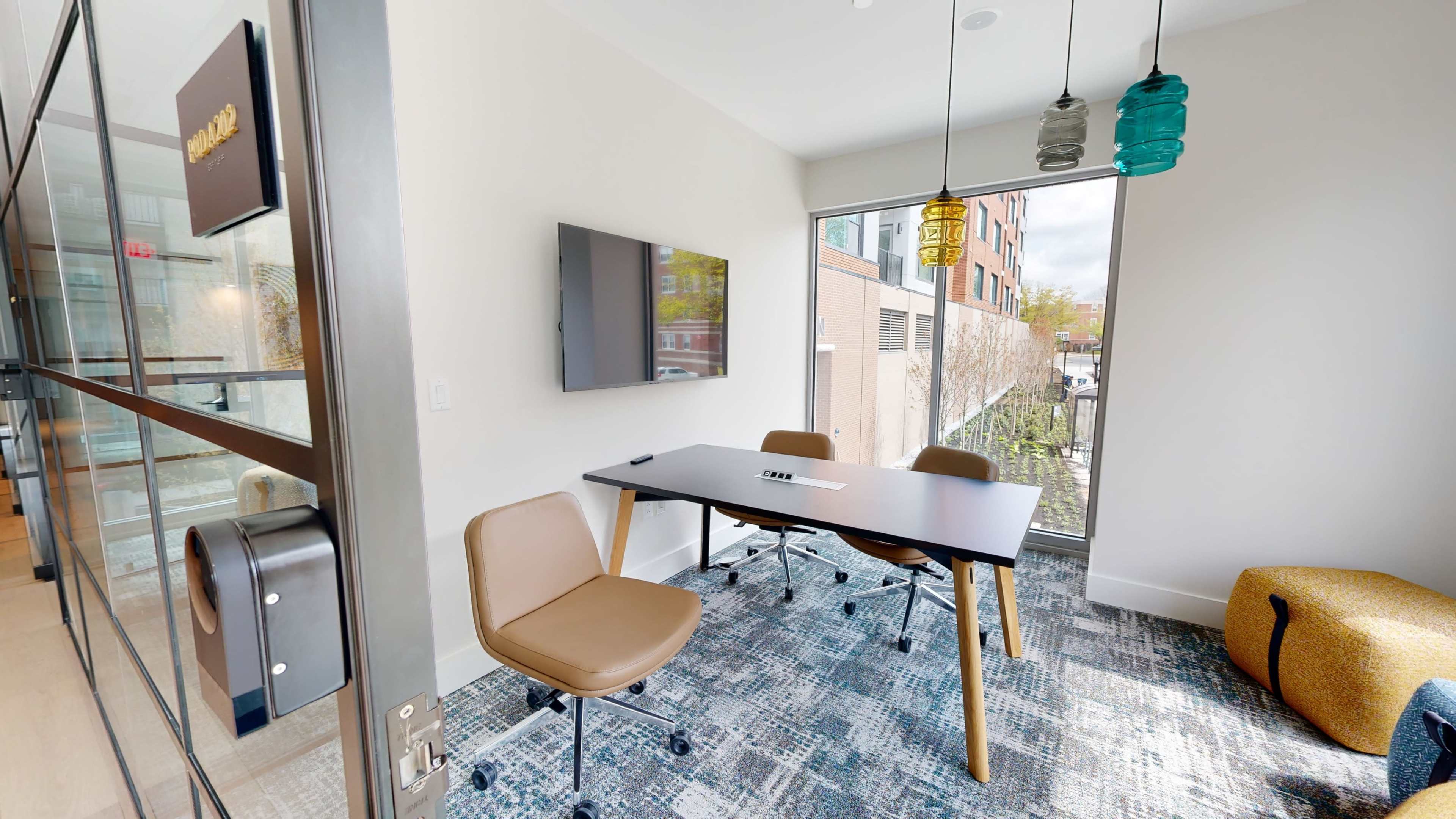 The image shows a modern meeting room with a table, chairs, and a TV, featuring large windows and colorful pendant lights.