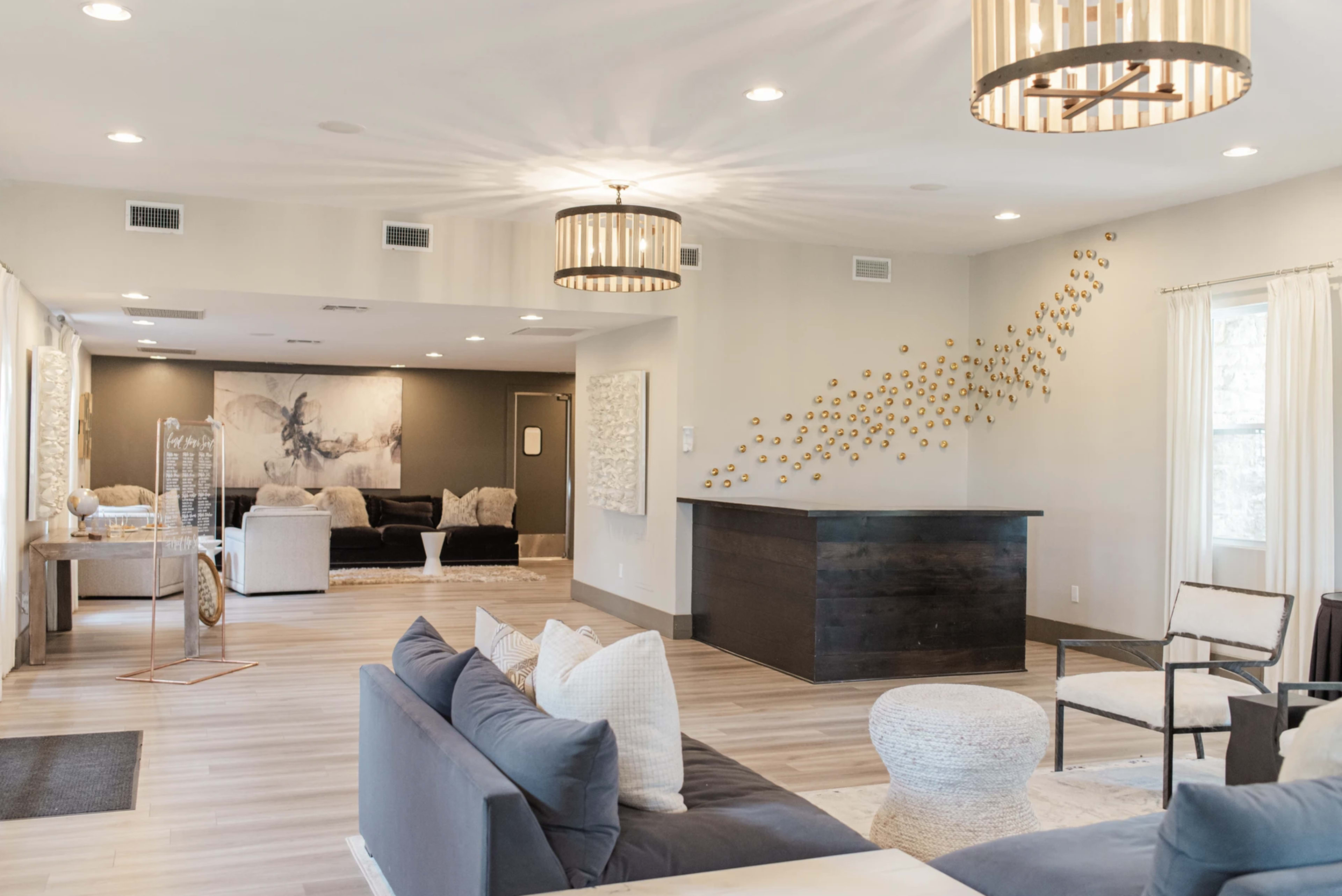 A spacious living area features a mix of seating arrangements, decorative lighting, and modern decor elements.