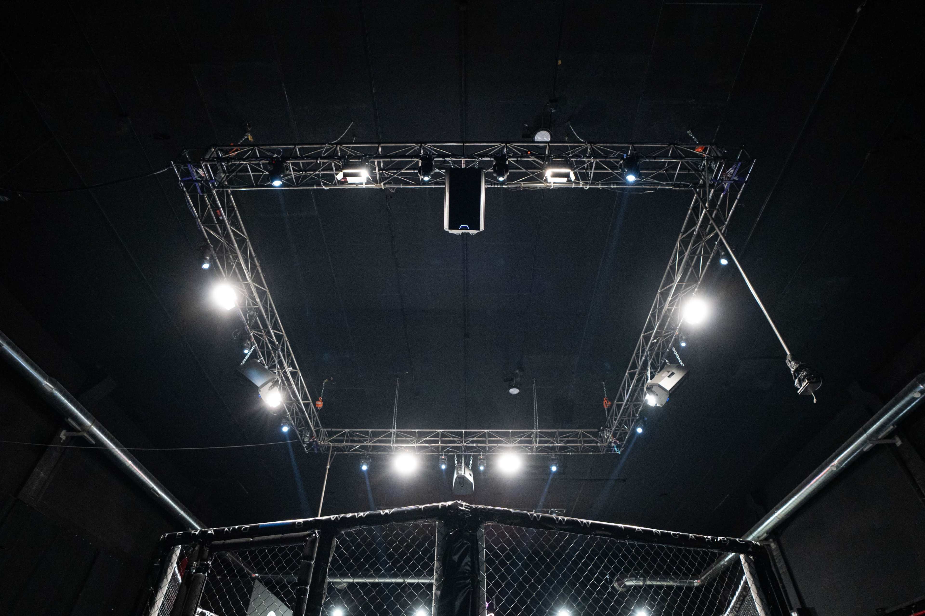 The image shows the overhead view of an octagonal cage with spotlights arranged around a rectangular truss framework in a dark venue.