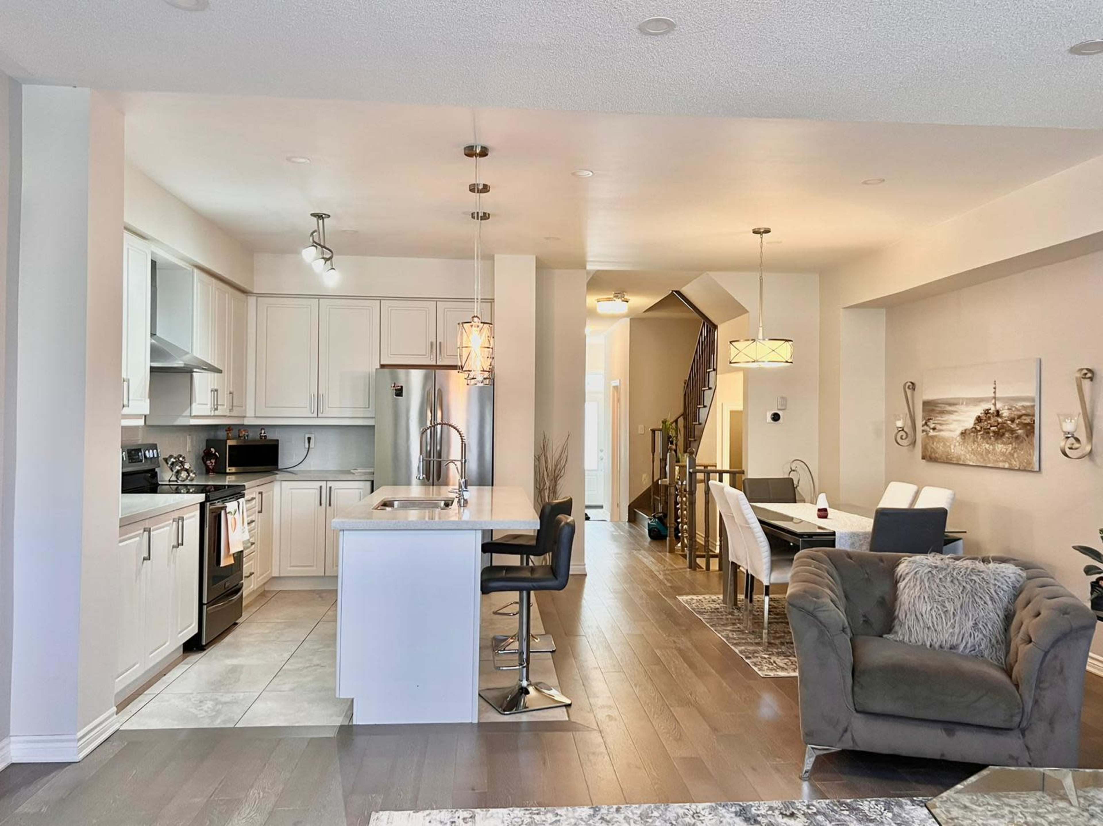 A modern open-concept kitchen and dining area with a staircase in the background.