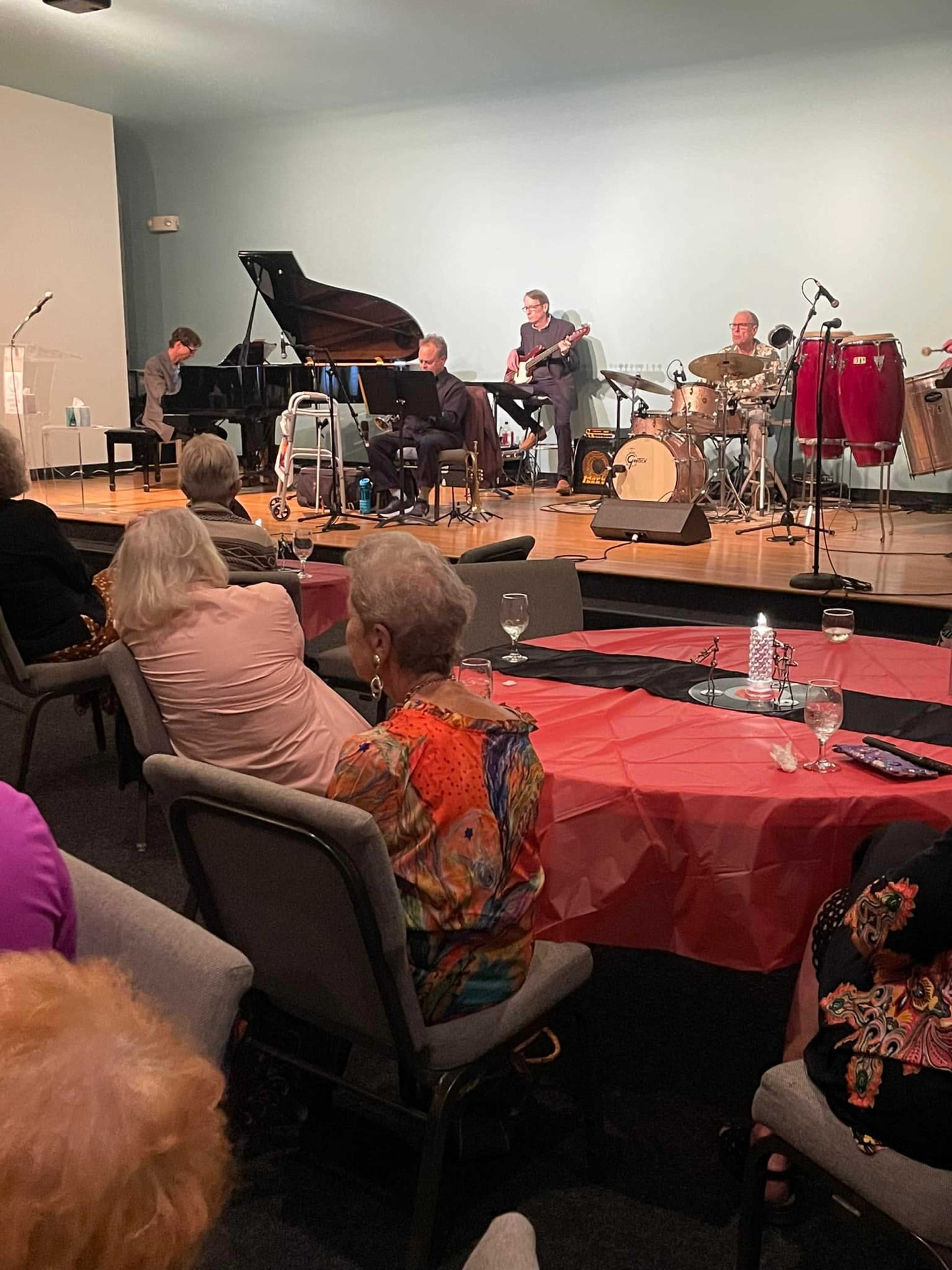 A jazz band performs on stage while an audience listens attentively from their seats.