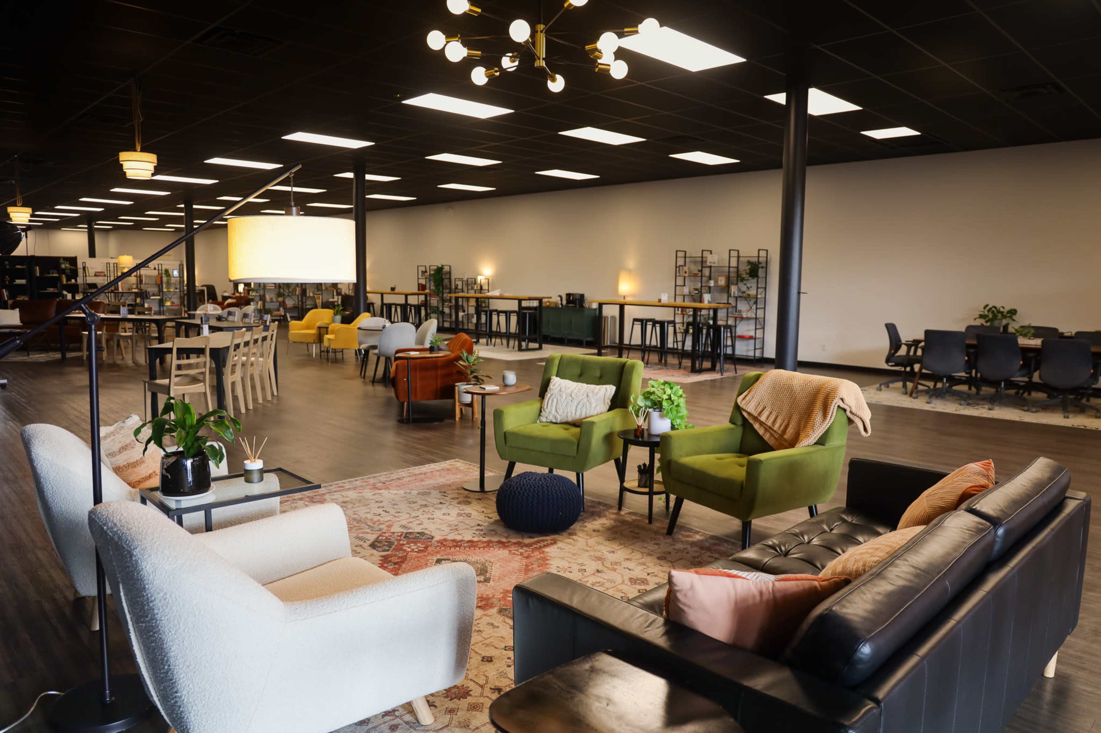 The image shows a spacious, modern interior featuring various seating arrangements, including sofas and chairs, along with tables and decorative plants.