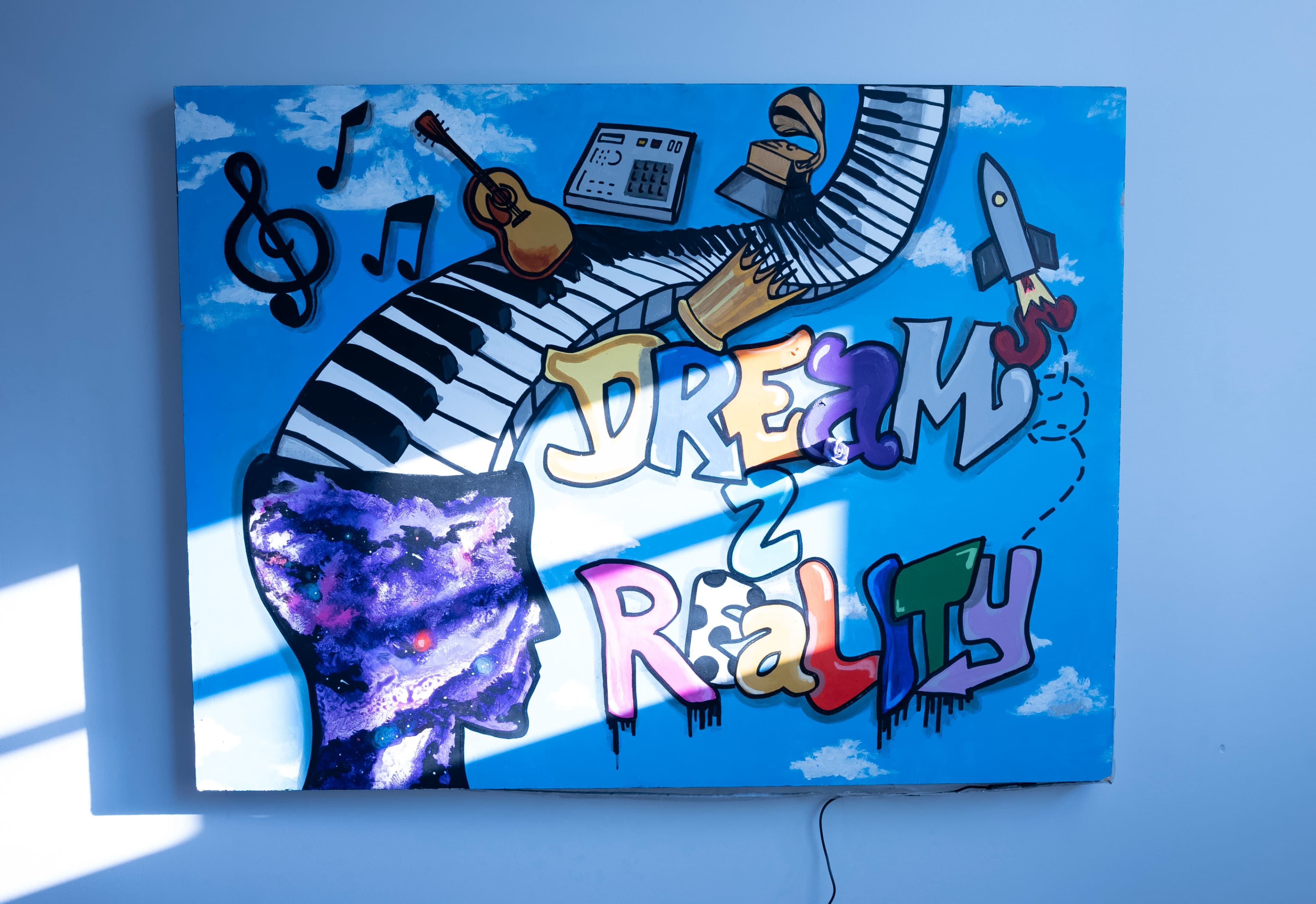 A colorful mural shows a head silhouette with musical elements and the phrase "DREAM 2 REALITY" against a blue background.