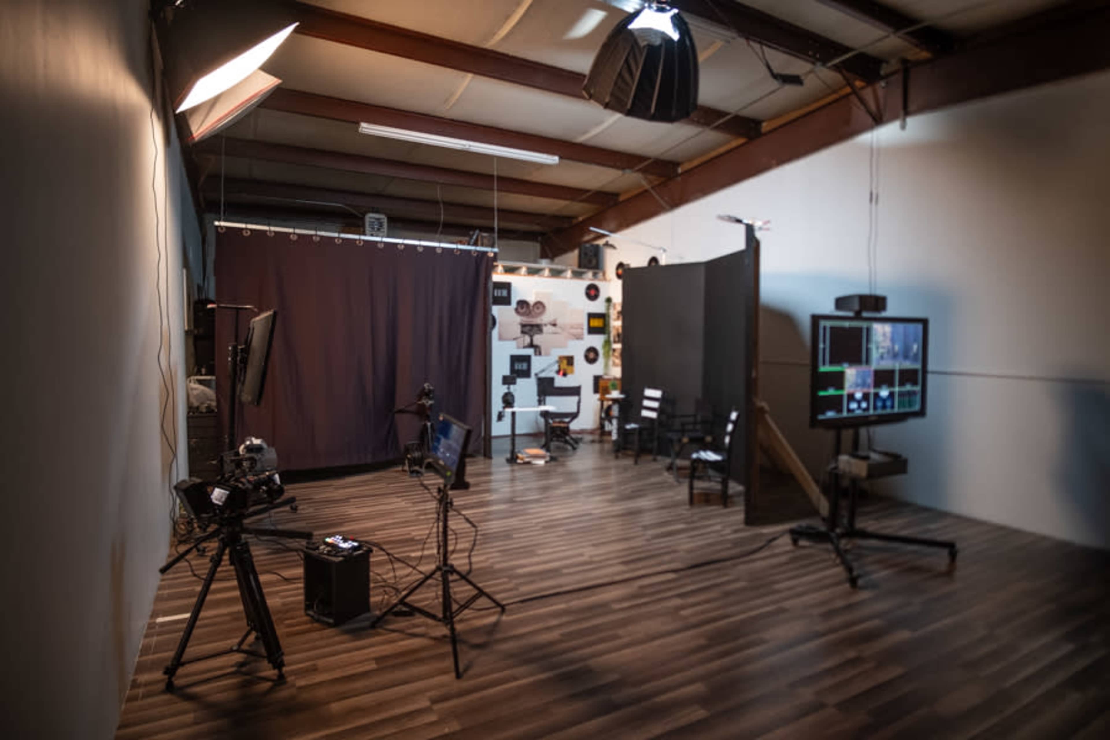 A photography studio with equipment including cameras, monitors, and a dark backdrop.
