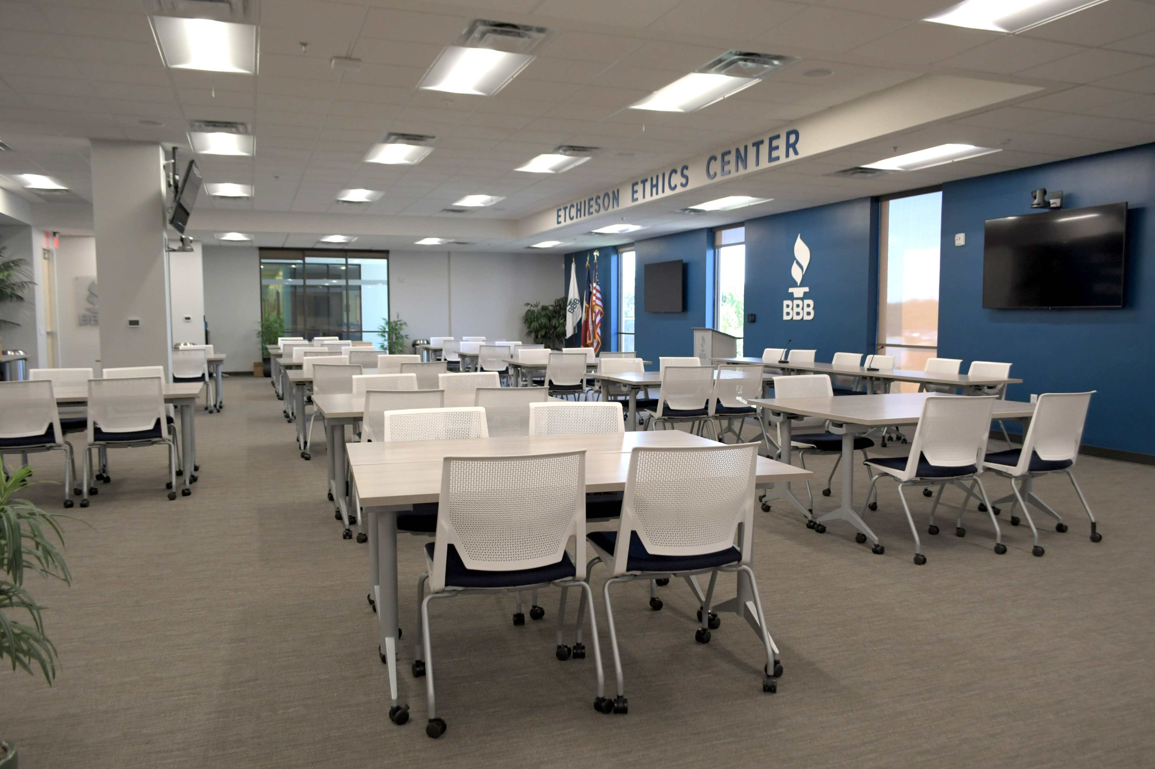 A spacious conference room set up with multiple tables and chairs, arranged for a meeting or workshop, with the "Ethics Center" sign on the wall.