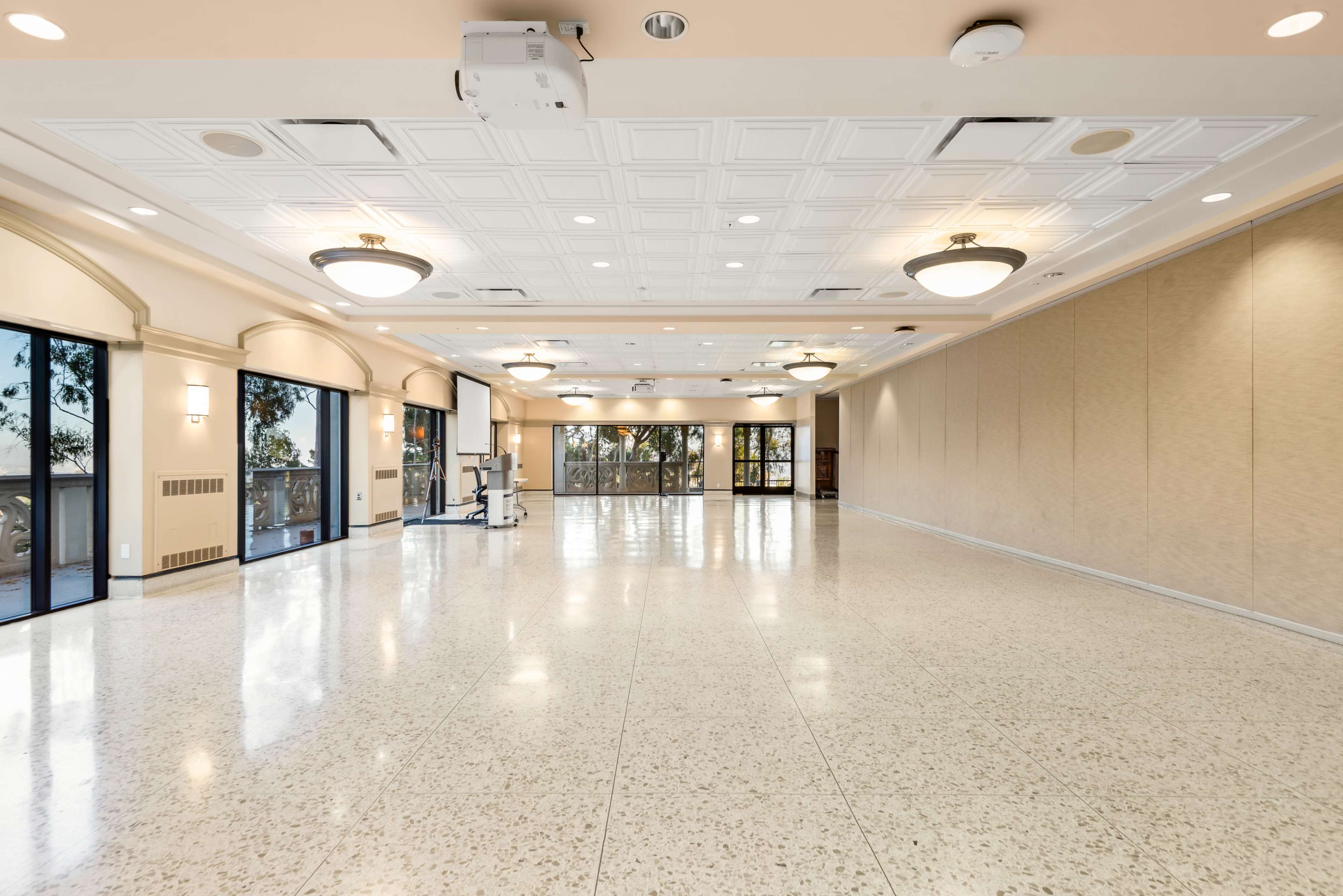 The image shows a spacious, empty event hall with large windows and a polished floor.
