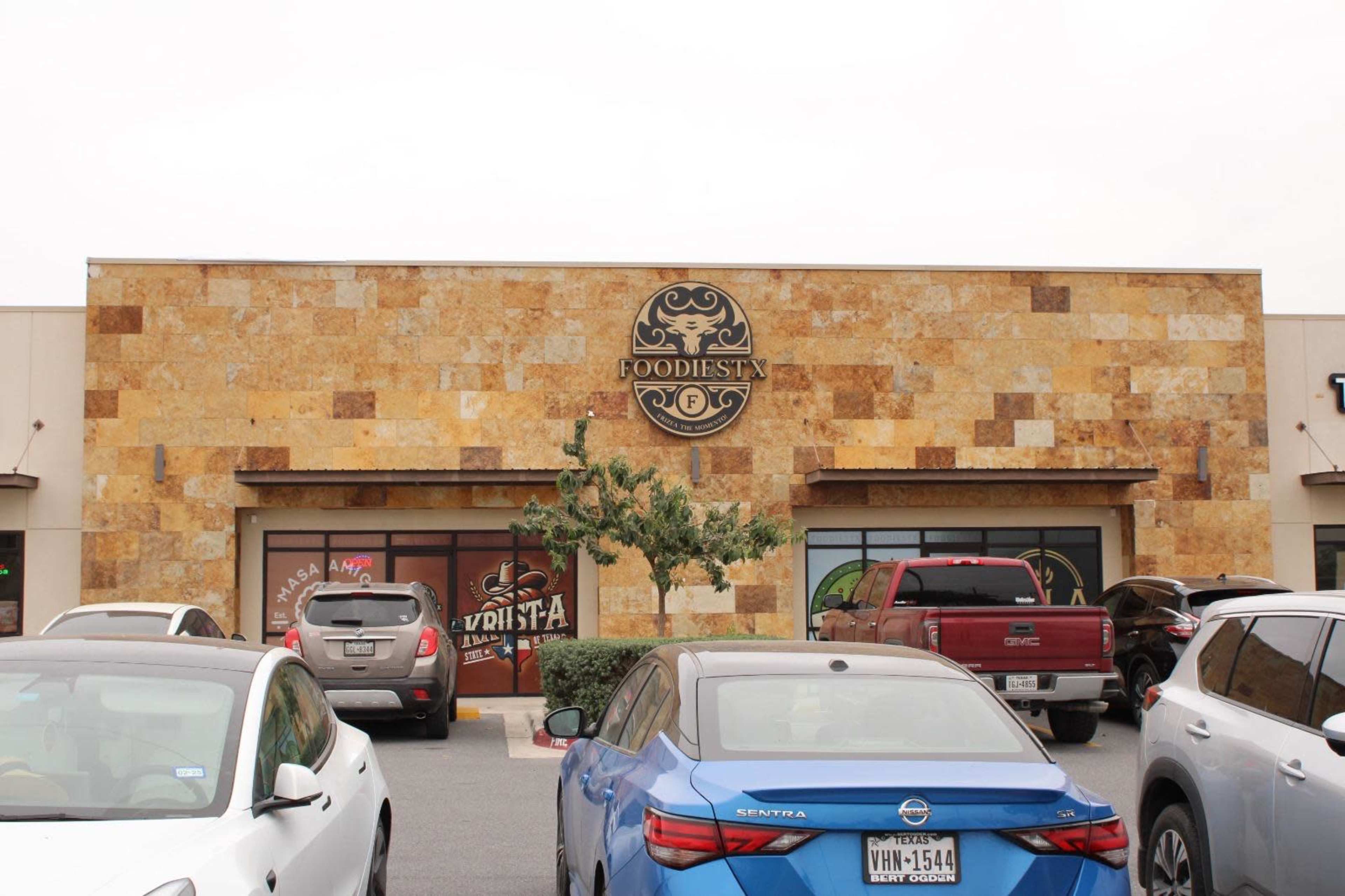 The image shows a restaurant named "Foodiesta" with a decorative stone facade and several parked cars in front.
