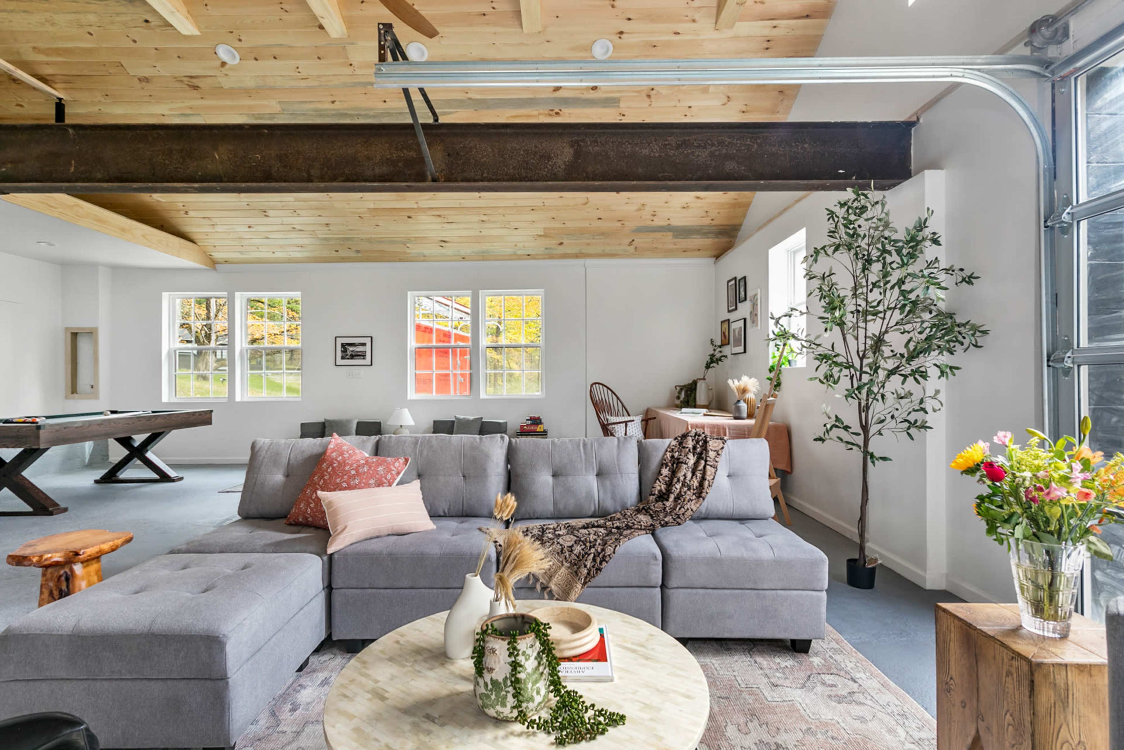 A modern open-concept living space featuring a gray sectional sofa, a round coffee table, and large windows illuminating the room.
